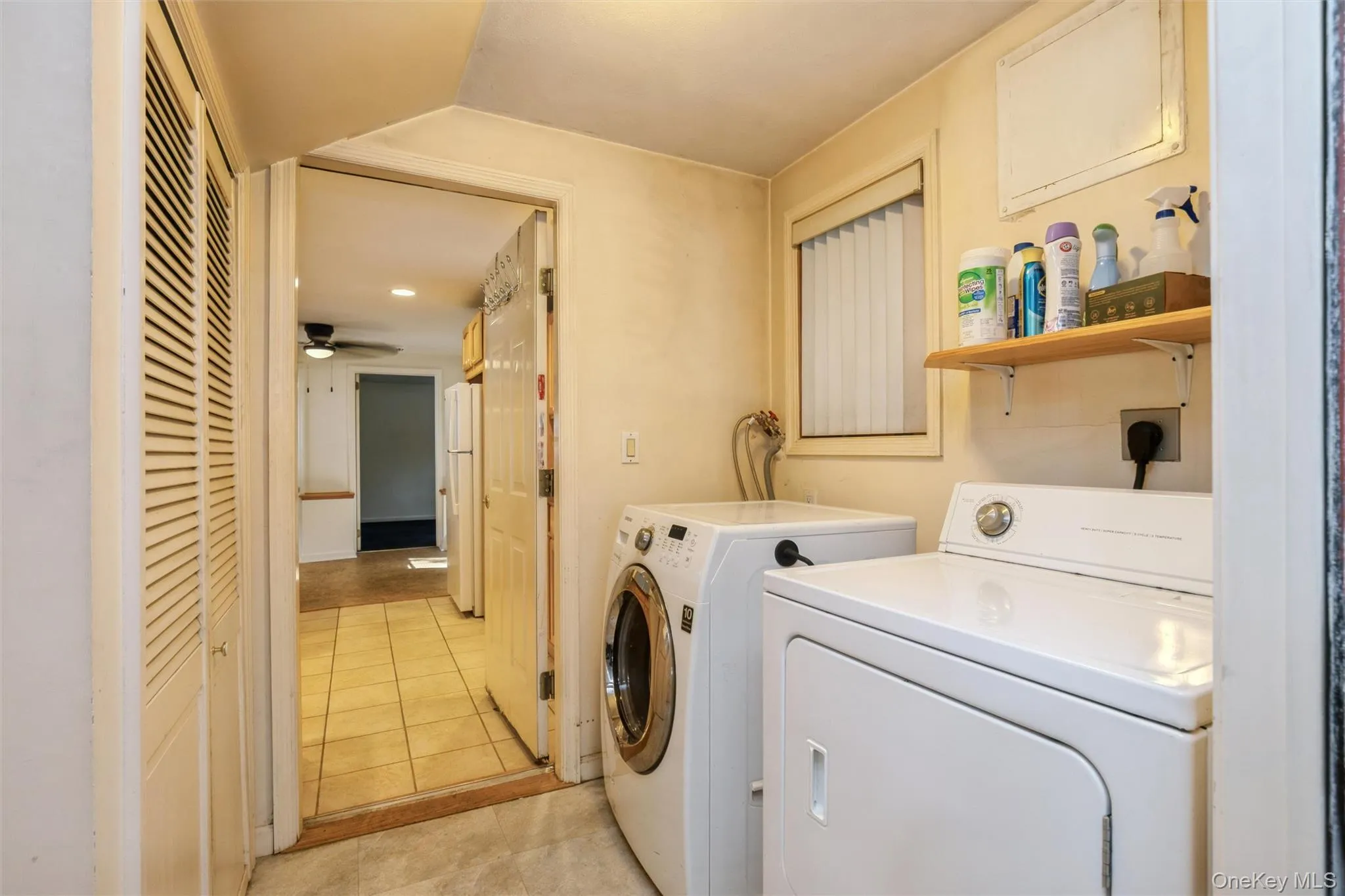 Dedicated laundry area featuring a louvered bi-fold closet and a window with blinds. Utilities Dedicated laundry area featuring a louvered bi-fold closet and a window with blinds. Utilities