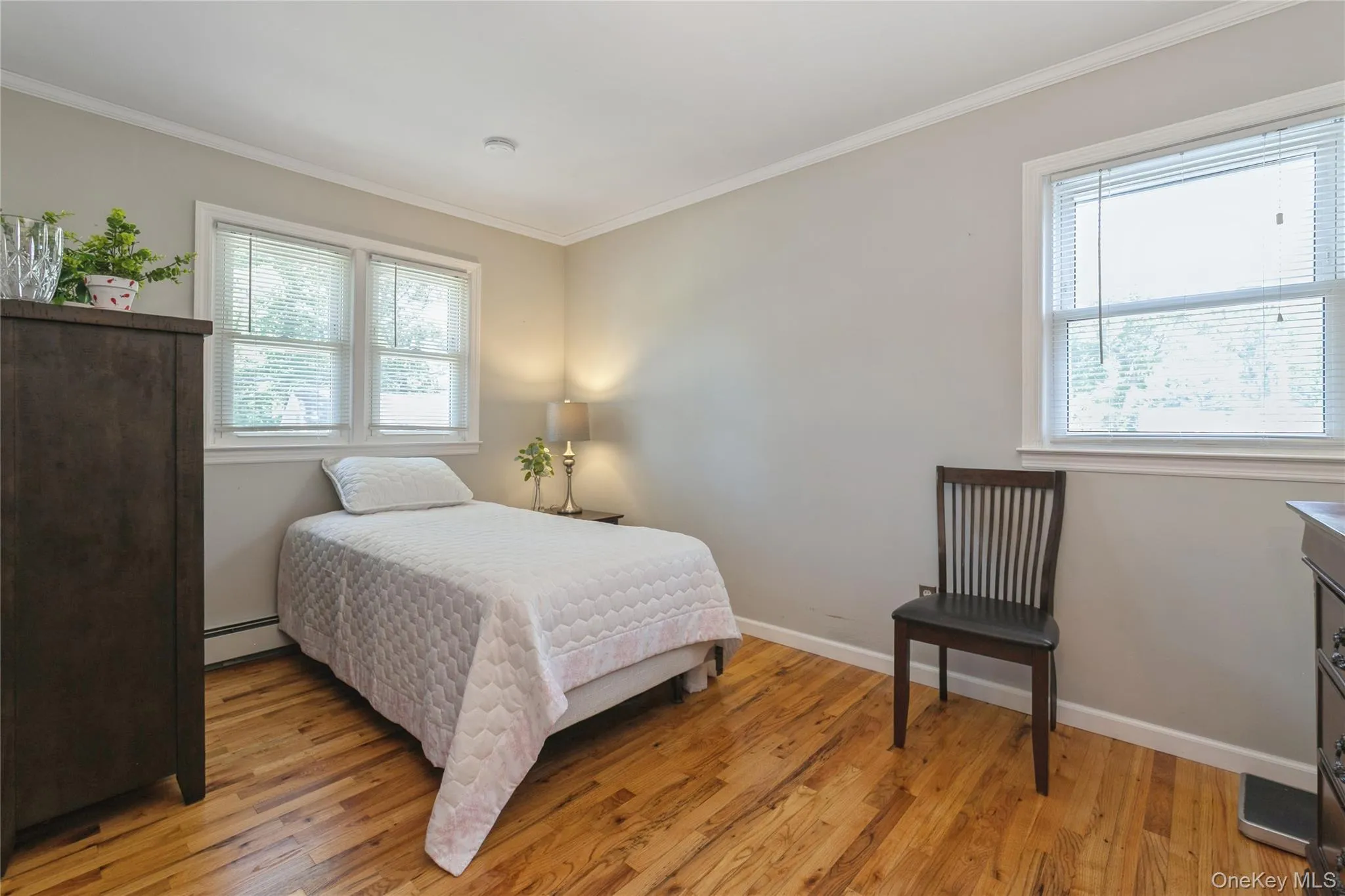 Bright room featuring polished wood-finish flooring and two distinct window openings Bright room featuring polished wood-finish flooring and two distinct window openings