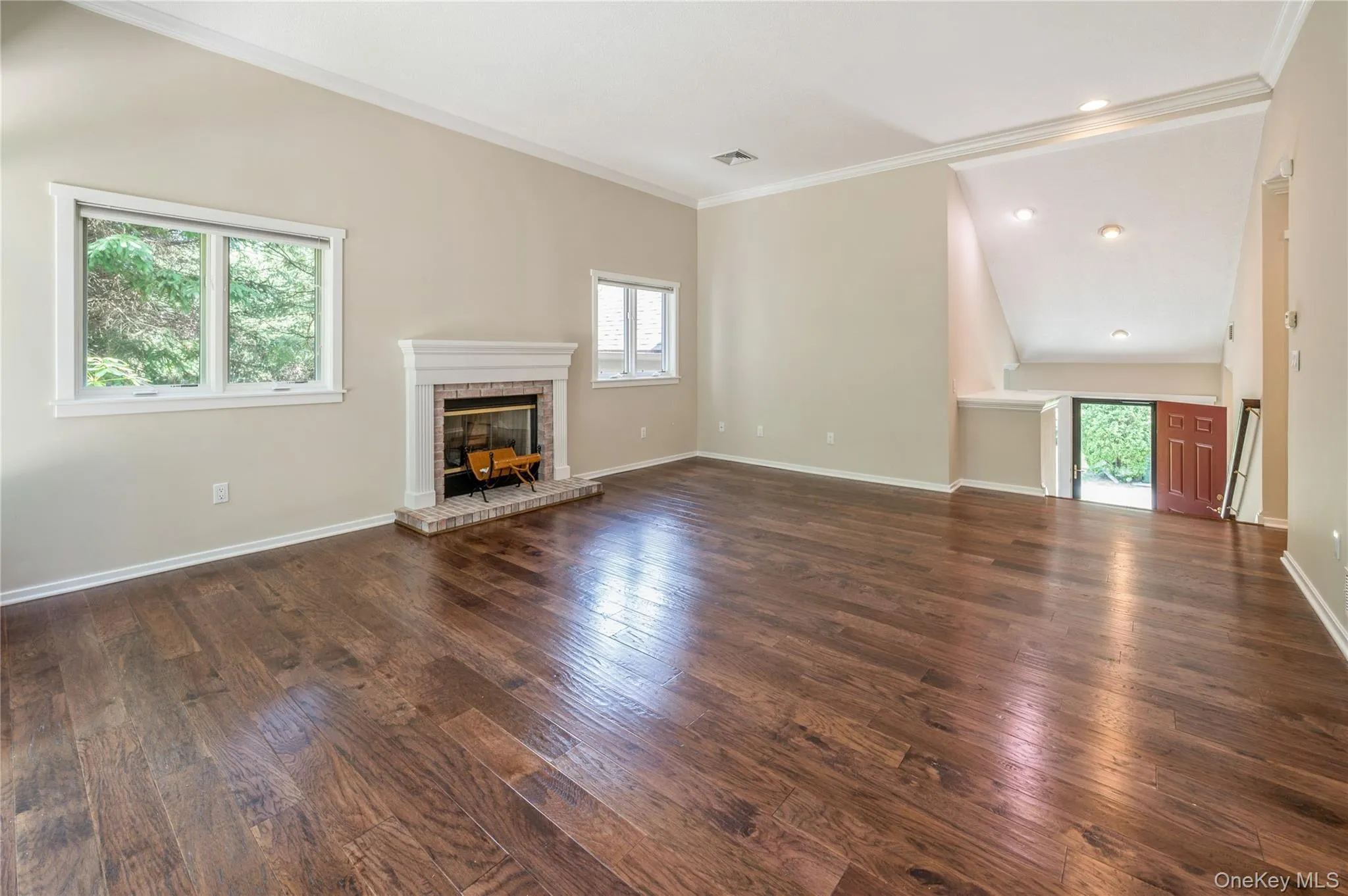 Unfurnished living room with a fireplace, dark wood-style flooring, and ornamental molding Unfurnished living room with a fireplace, dark wood-style flooring, and ornamental molding