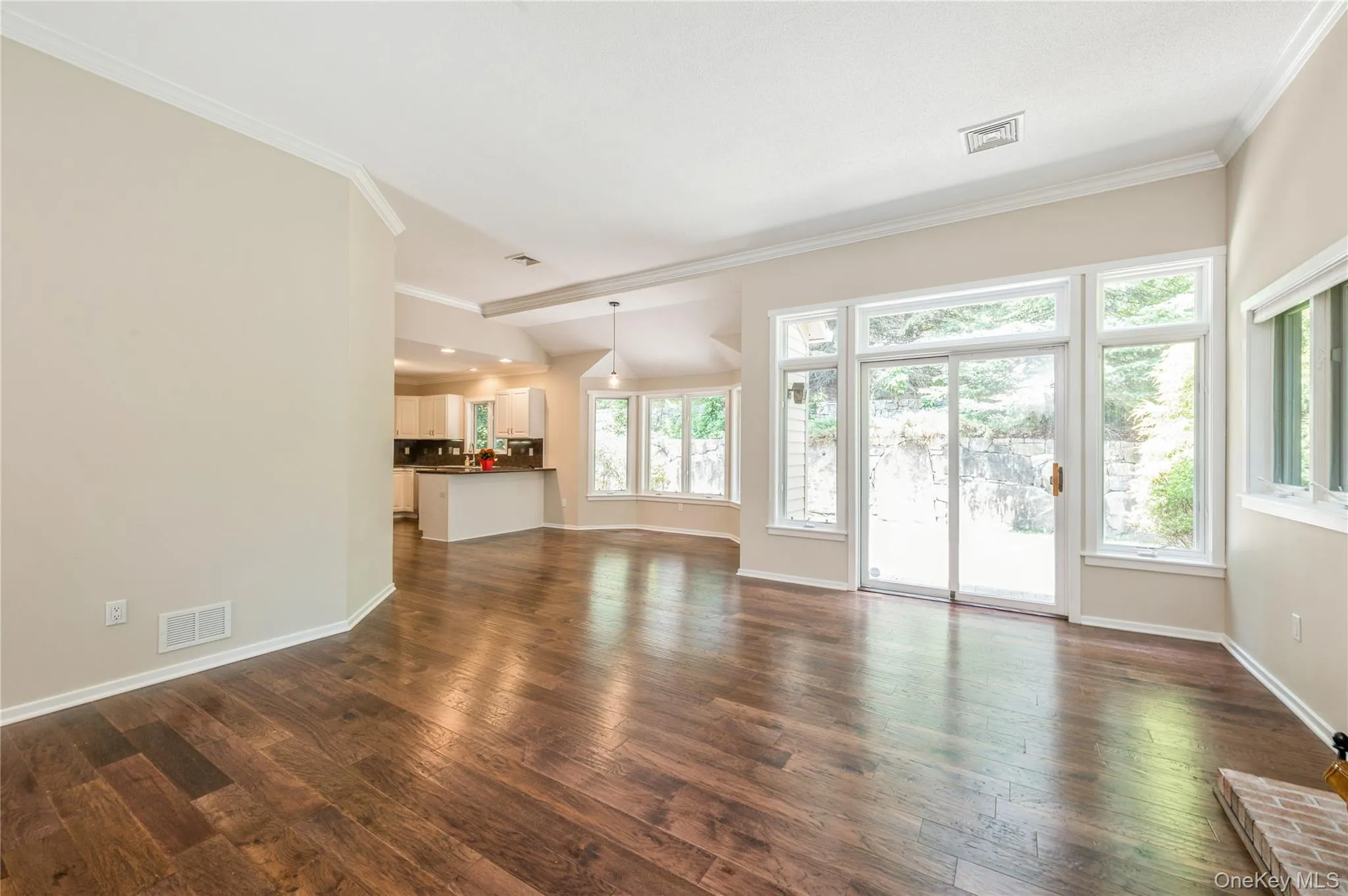 Unfurnished living room featuring ornamental molding and dark wood-style floors Unfurnished living room featuring ornamental molding and dark wood-style floors