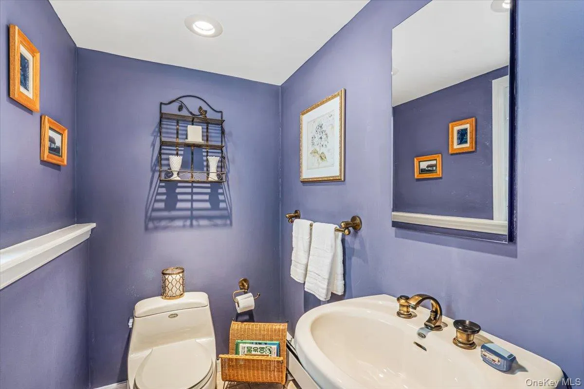 Half bathroom featuring a white toilet, recessed lighting, wall-mounted mirror, and a classic pedestal sink with brass-finish fixtures Half bathroom featuring a white toilet, recessed lighting, wall-mounted mirror, and a classic pedestal sink with brass-finish fixtures