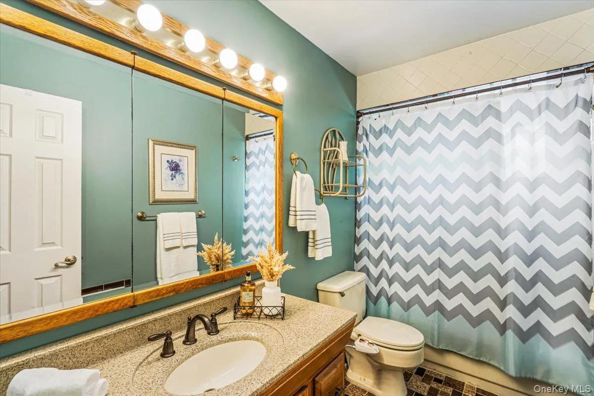 Primary bathroom featuring a vanity with a speckled countertop and integrated sink, bronze-finish faucet, and wood-framed mirrored medicine cabinet Primary bathroom featuring a vanity with a speckled countertop and integrated sink, bronze-finish faucet, and wood-framed mirrored medicine cabinet
