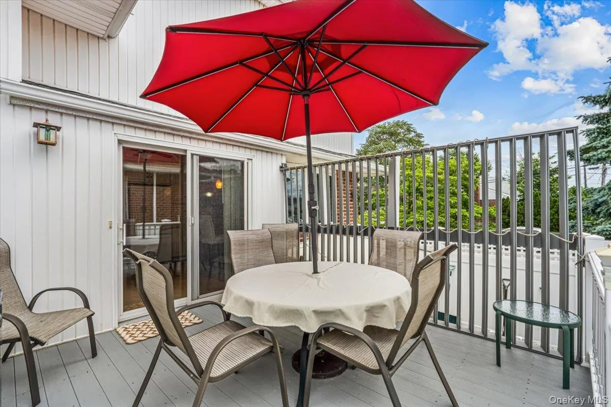 Outdoor deck featuring a sliding glass door, white vertical siding, and grey plank flooring Outdoor deck featuring a sliding glass door, white vertical siding, and grey plank flooring