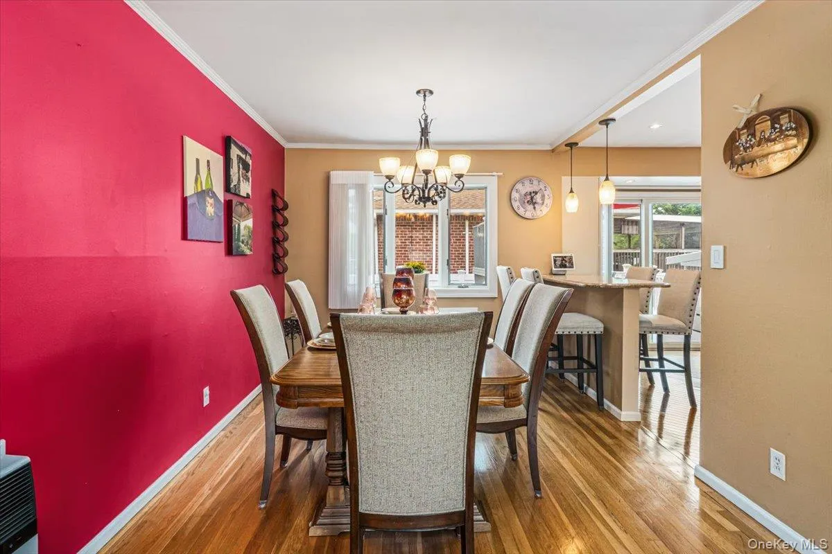 Dining area featuring wood-finish flooring, a chandelier, and a breakfast bar with pendant lighting Dining area featuring wood-finish flooring, a chandelier, and a breakfast bar with pendant lighting
