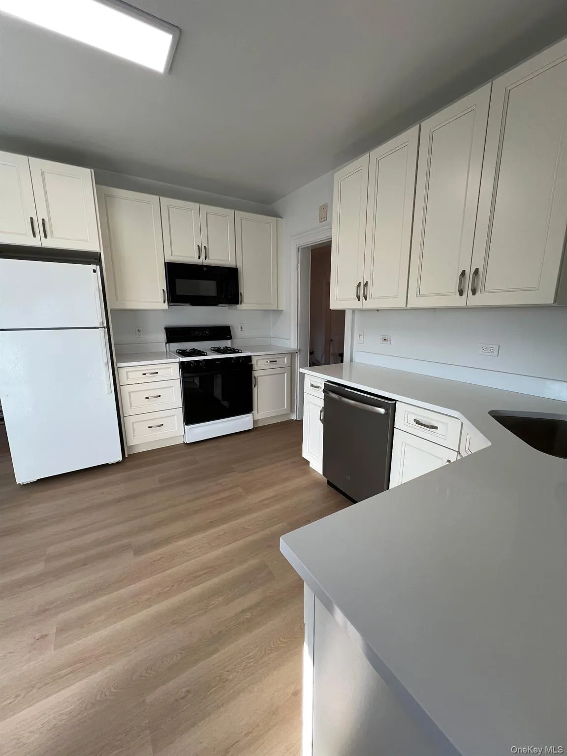 Kitchen featuring light countertops, gas stove, stainless steel dishwasher, freestanding refrigerator, and black microwave Kitchen featuring light countertops, gas stove, stainless steel dishwasher, freestanding refrigerator, and black microwave
