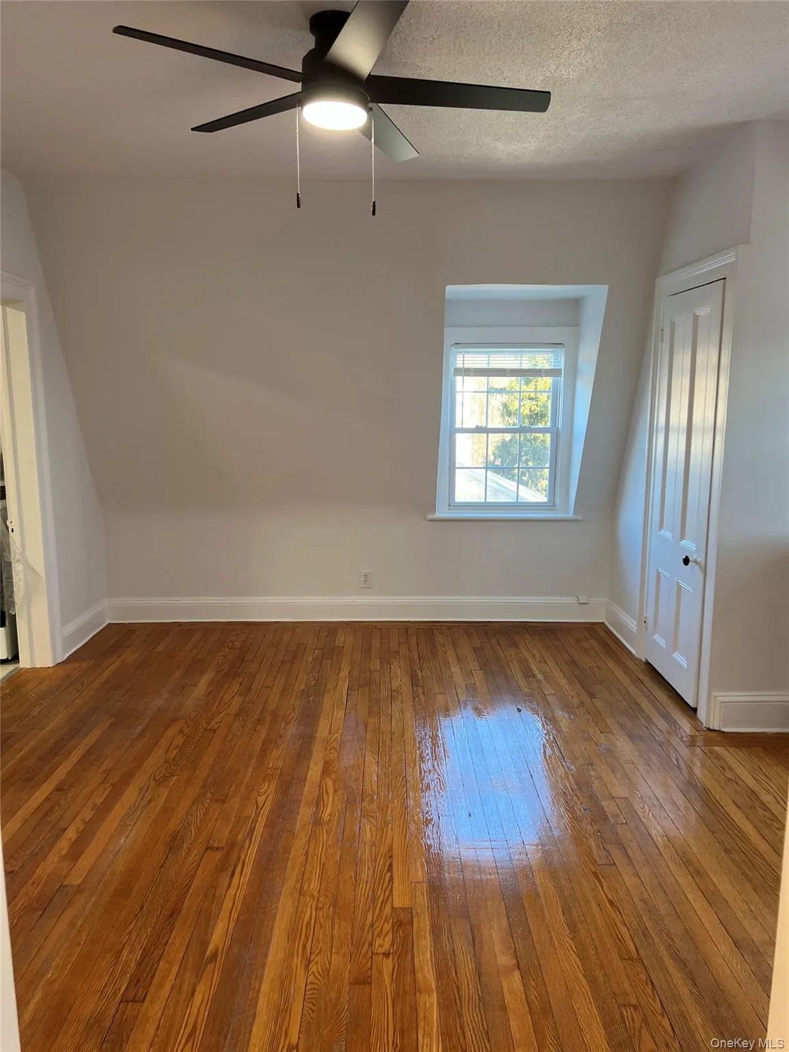 Unfurnished room with hardwood / wood-style floors, a ceiling fan, baseboards, and a textured ceiling Unfurnished room with hardwood / wood-style floors, a ceiling fan, baseboards, and a textured ceiling