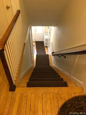 Stairway featuring a wainscoted wall, a decorative wall, and hardwood / wood-style floors Stairway featuring a wainscoted wall, a decorative wall, and hardwood / wood-style floors