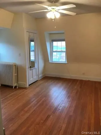Bonus room with a ceiling fan, radiator, baseboards, and wood finished floors Bonus room with a ceiling fan, radiator, baseboards, and wood finished floors