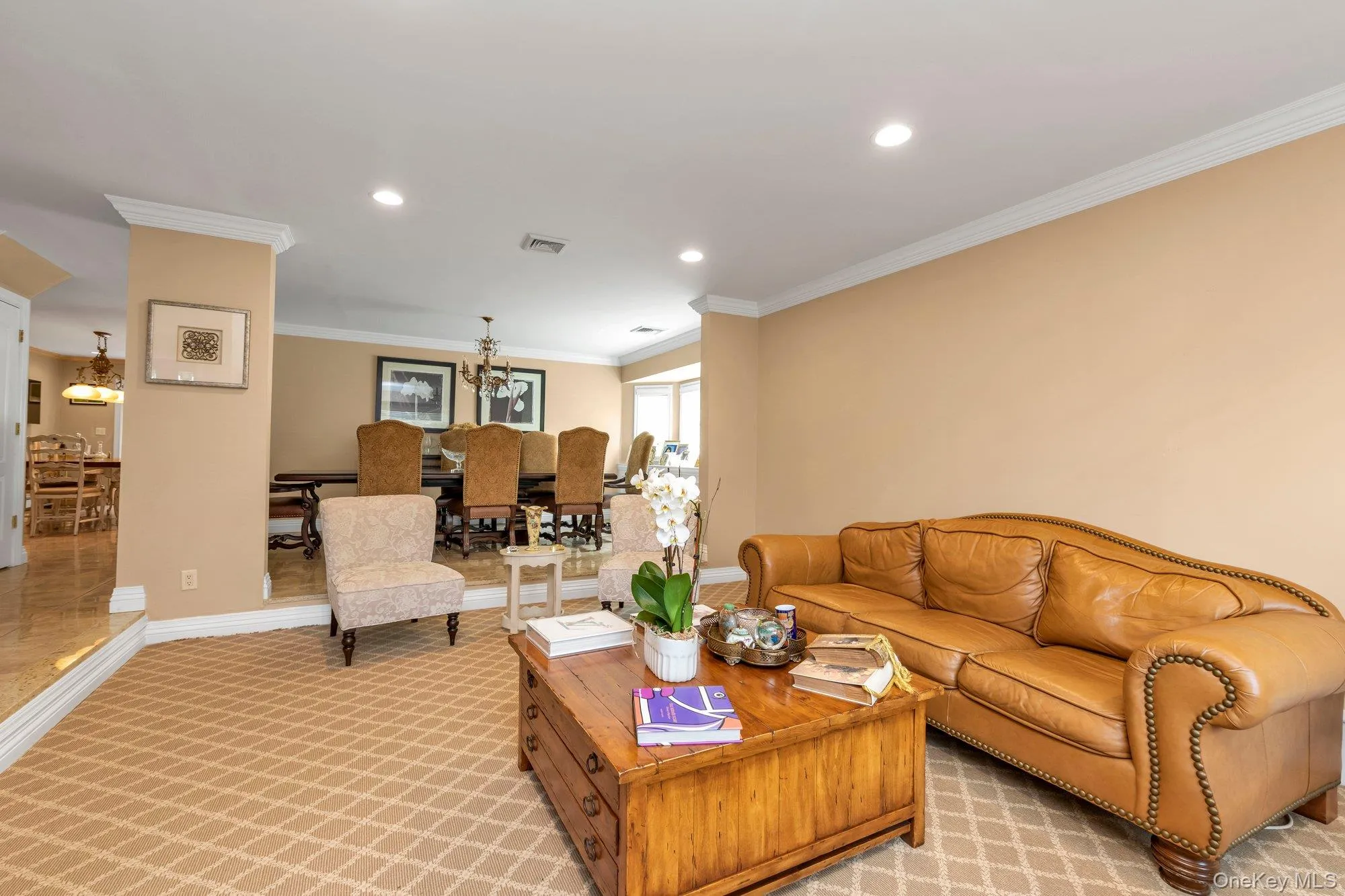 Carpeted living area with recessed lighting, crown molding, and a partial wall separating a dining area Carpeted living area with recessed lighting, crown molding, and a partial wall separating a dining area