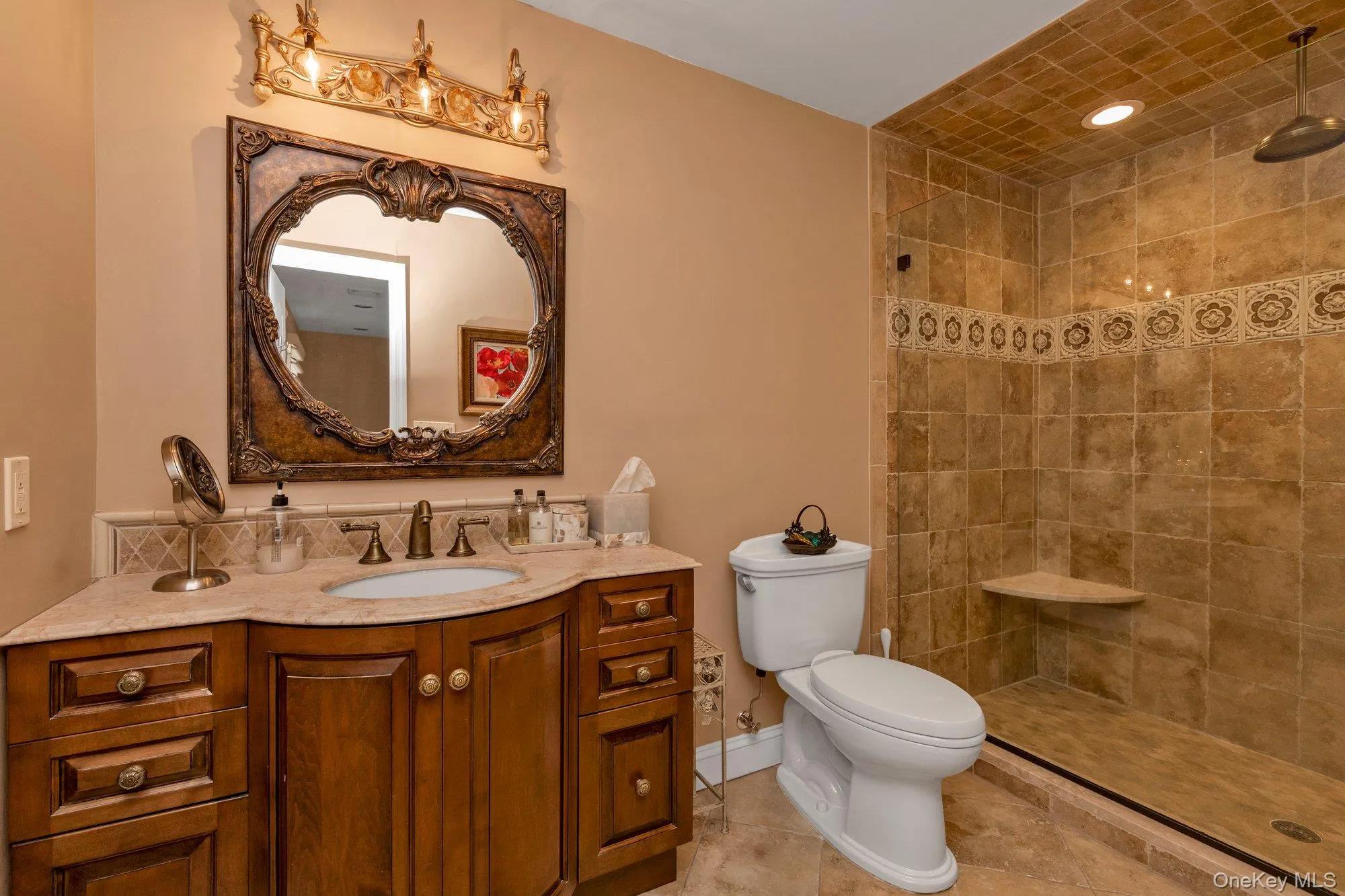 Bathroom featuring a curved wood-finish vanity with an undermount sink, a granite countertop, and a decorative mirror Bathroom featuring a curved wood-finish vanity with an undermount sink, a granite countertop, and a decorative mirror
