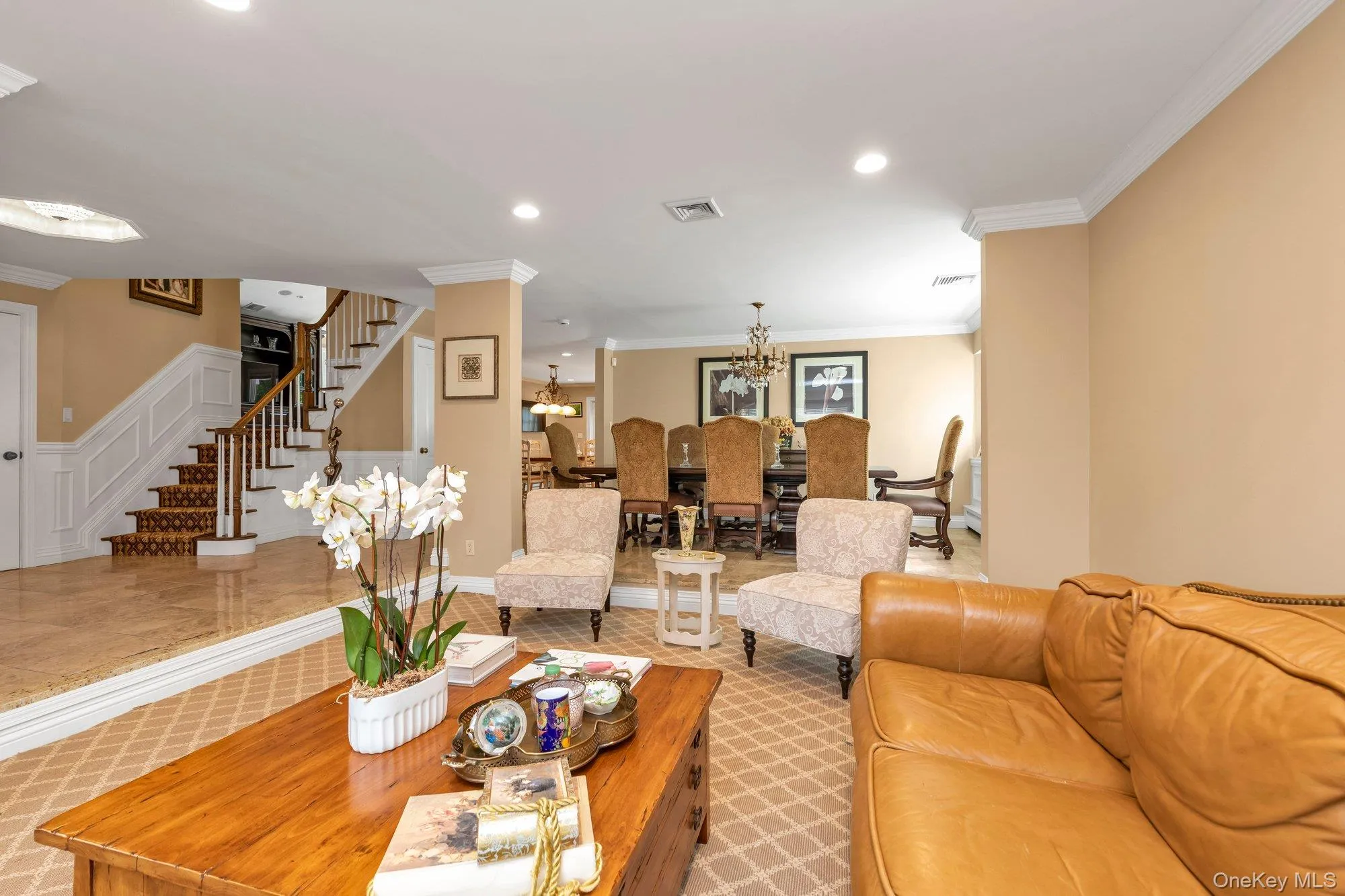 Elegant interior featuring a grand staircase with wood newel posts and balusters, wainscoting, and a tiled entryway Elegant interior featuring a grand staircase with wood newel posts and balusters, wainscoting, and a tiled entryway