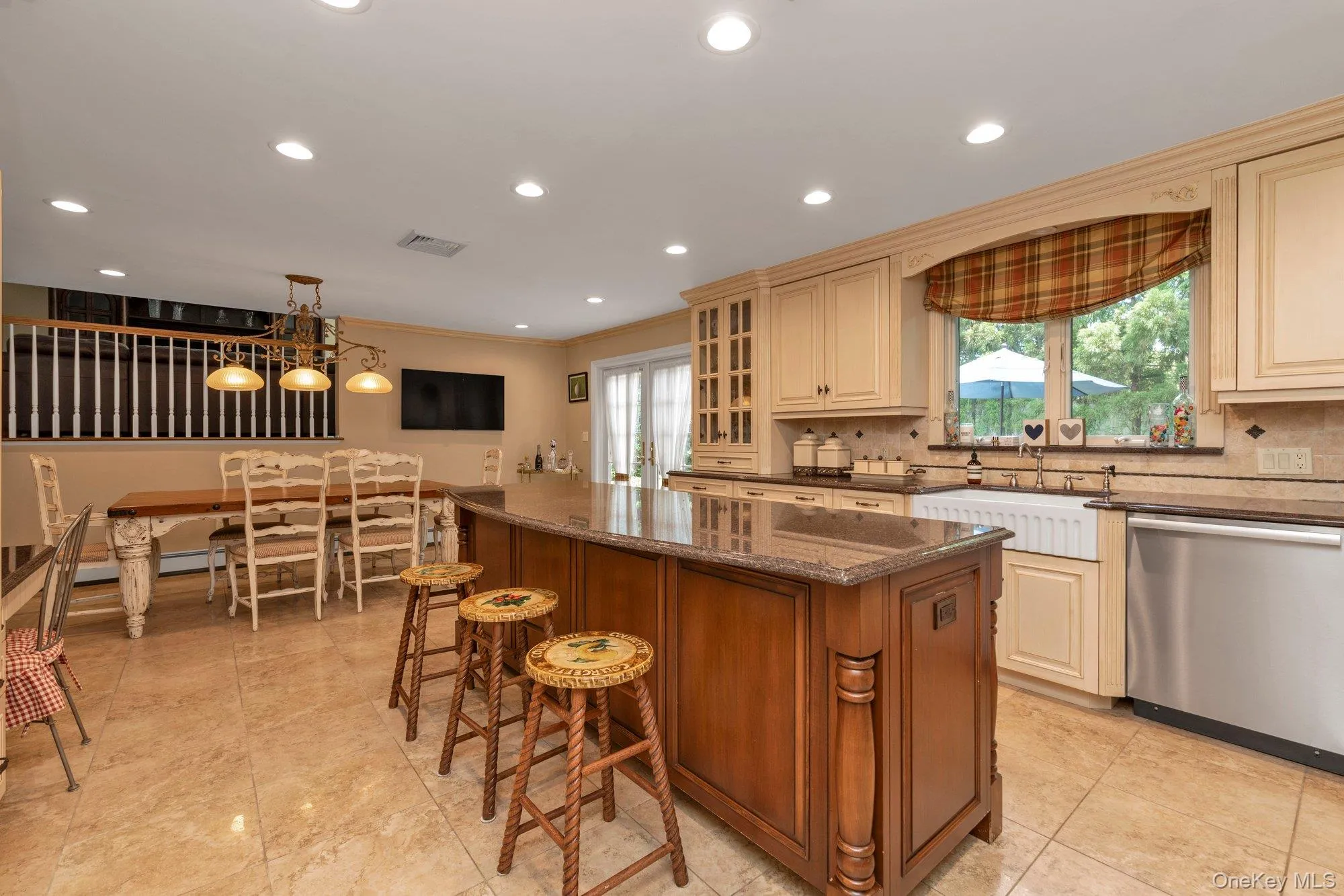 Open concept kitchen featuring an island with a stone countertop, light-toned cabinetry, stainless steel appliances, a farmhouse-style sink, and recessed lighting Open concept kitchen featuring an island with a stone countertop, light-toned cabinetry, stainless steel appliances, a farmhouse-style sink, and recessed lighting