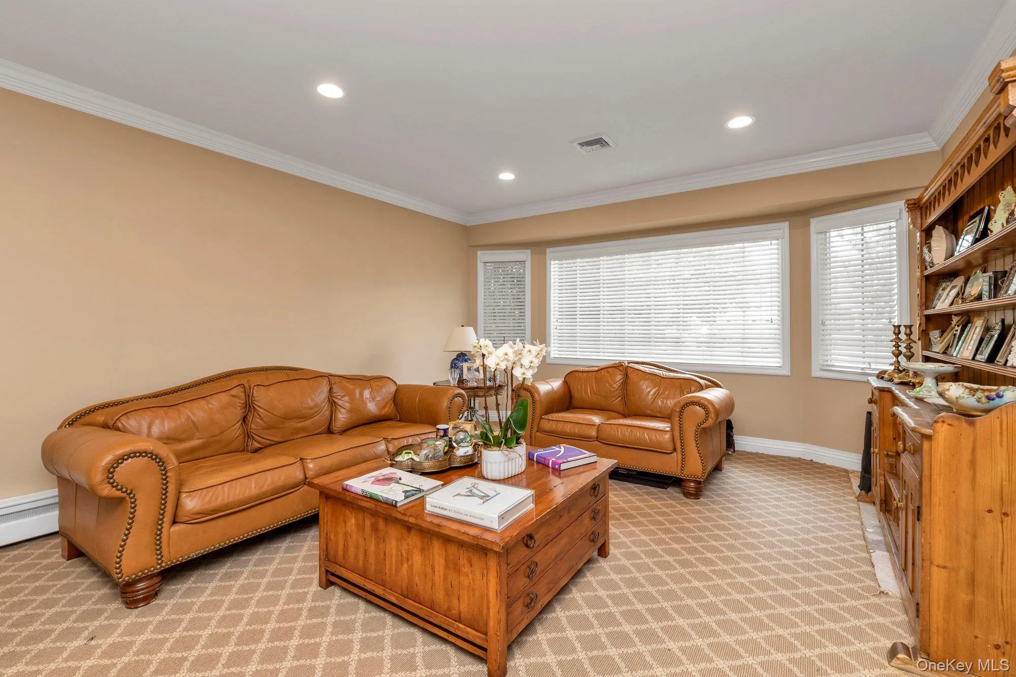 Spacious living room featuring neutral-toned walls, recessed lighting, and crown molding Spacious living room featuring neutral-toned walls, recessed lighting, and crown molding