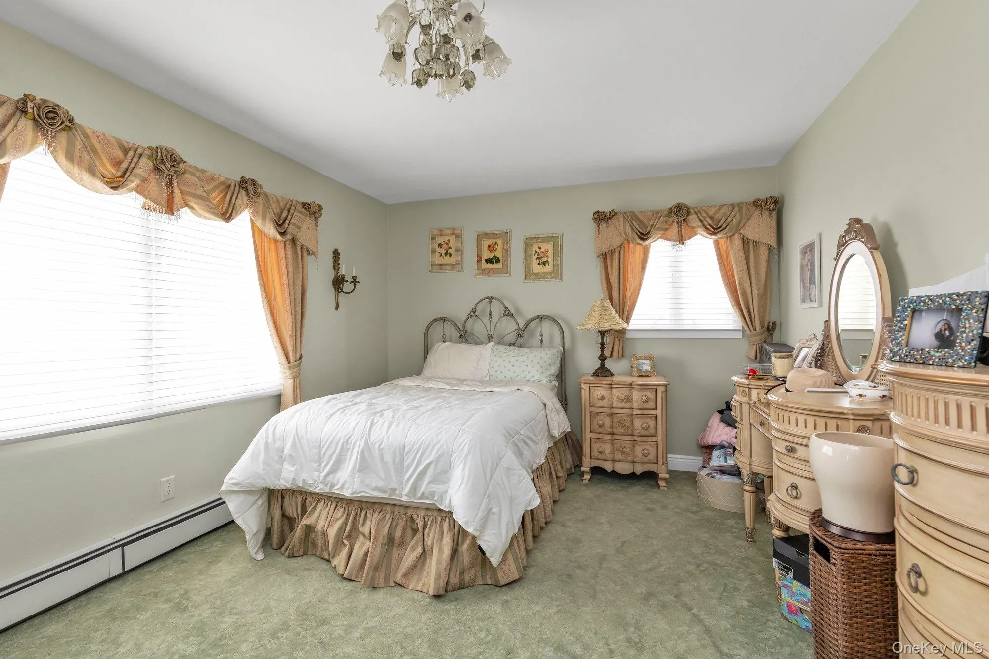Spacious interior room featuring ample natural light from two large windows, overhead chandelier lighting, wall sconce lighting, and soft green carpeting Spacious interior room featuring ample natural light from two large windows, overhead chandelier lighting, wall sconce lighting, and soft green carpeting