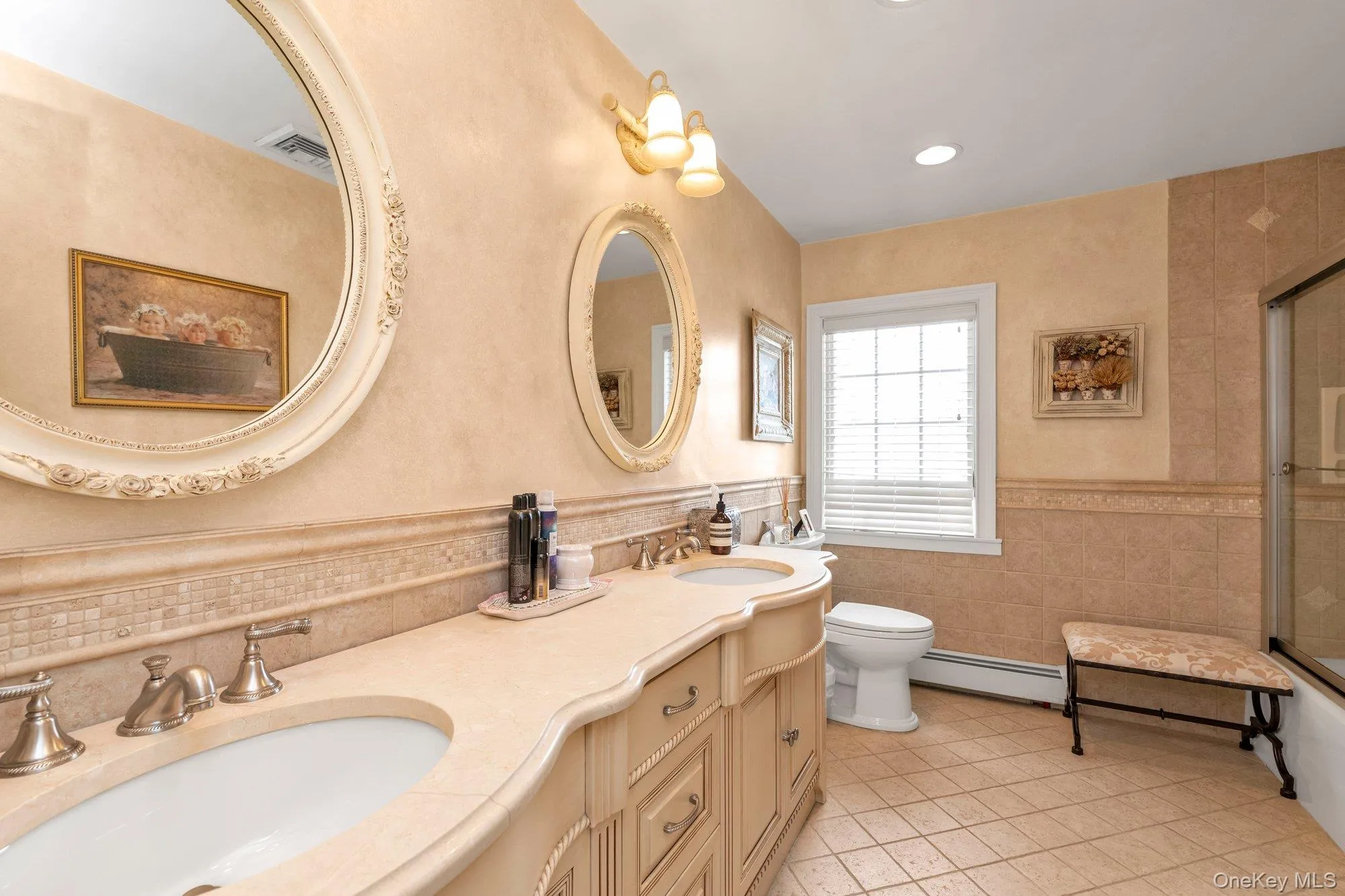 Bathroom featuring a double vanity with undermount sinks, decorative framed mirrors, and a tiled shower with a glass enclosure Bathroom featuring a double vanity with undermount sinks, decorative framed mirrors, and a tiled shower with a glass enclosure