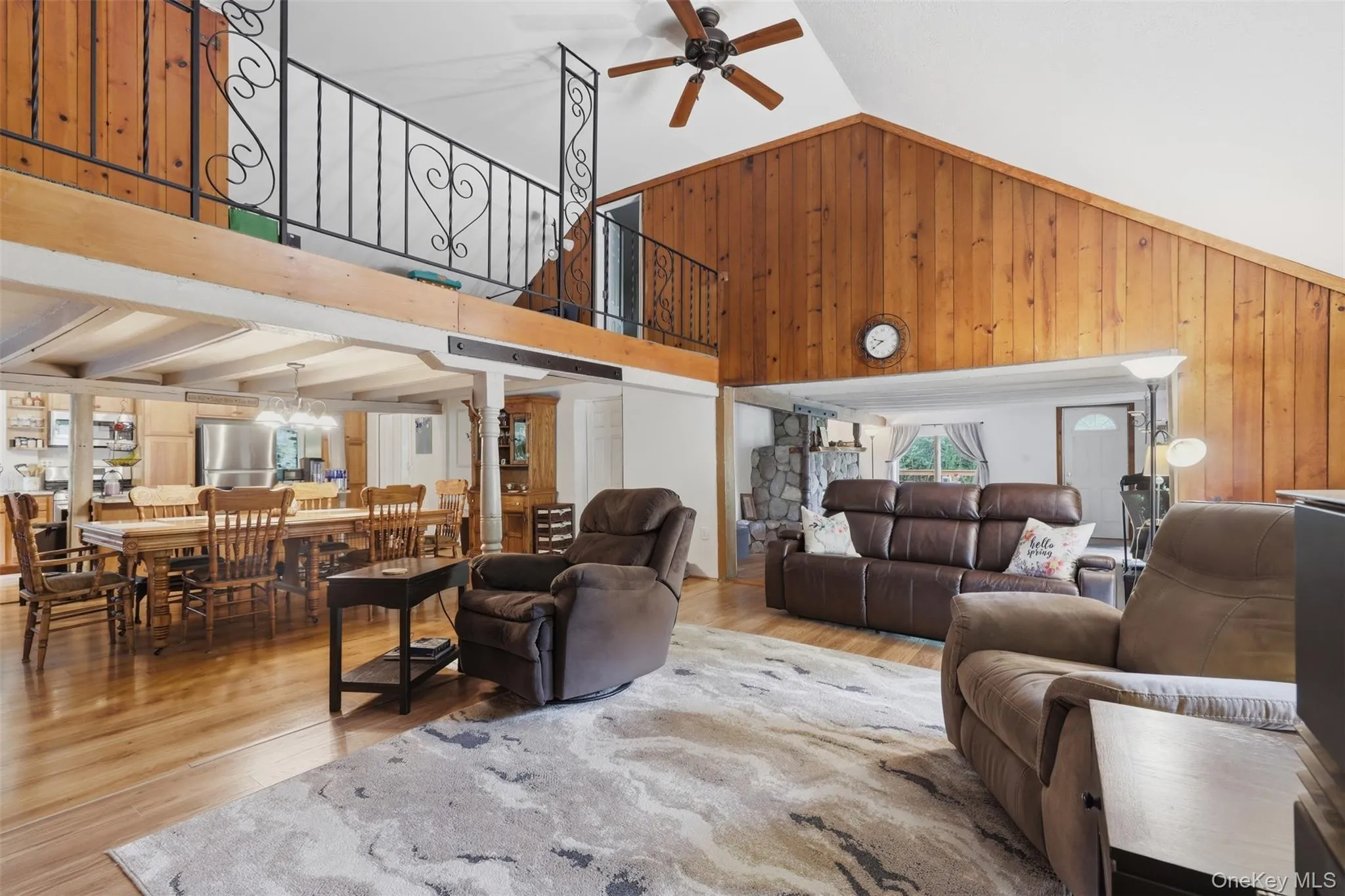 Spacious interior featuring a vaulted wood-paneling, wood-finish flooring, and a loft with decorative wrought iron railing Spacious interior featuring a vaulted wood-paneling, wood-finish flooring, and a loft with decorative wrought iron railing