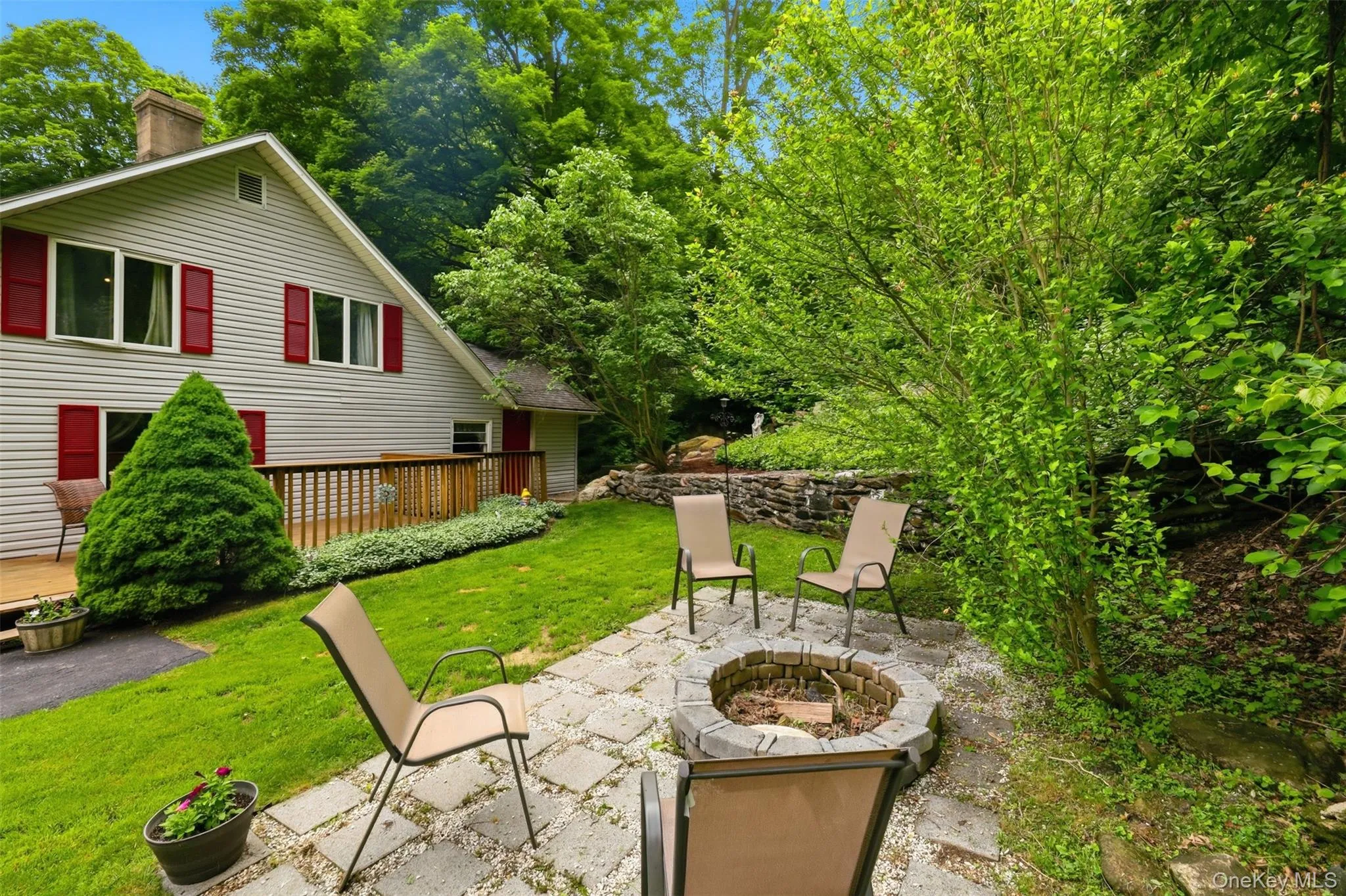 Relaxing outdoor living area featuring a stone fire pit, paver patio, and a wooden deck Relaxing outdoor living area featuring a stone fire pit, paver patio, and a wooden deck