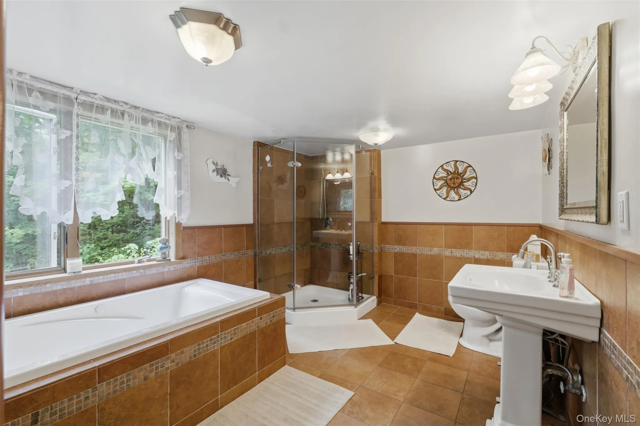 Bathroom featuring a built-in tub with tile surround, a corner glass-enclosed shower, and a pedestal sink Bathroom featuring a built-in tub with tile surround, a corner glass-enclosed shower, and a pedestal sink