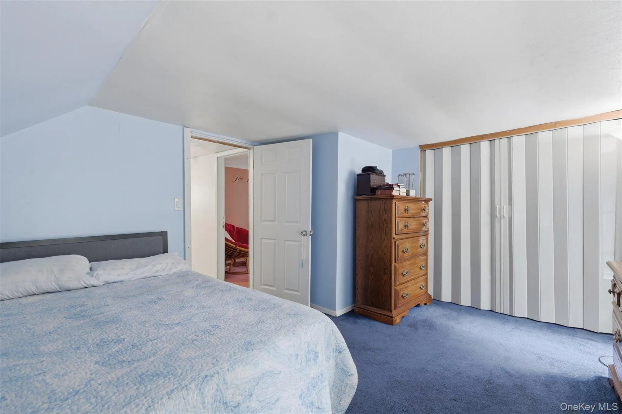 Upstairs bedroom #1 with blue wall paint complementing blue carpeting, with a white accordion closet door system Upstairs bedroom #1 with blue wall paint complementing blue carpeting, with a white accordion closet door system