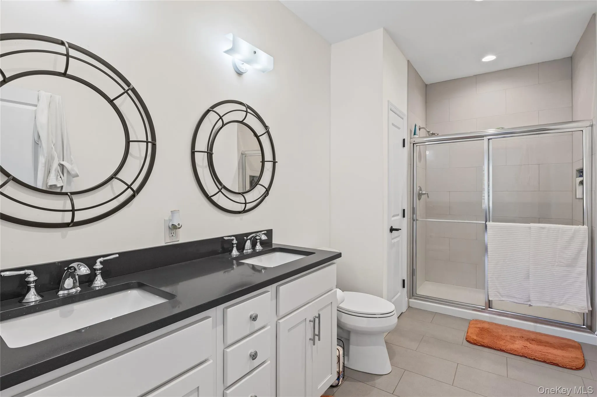 Full bathroom featuring double vanity, a shower stall, light tile patterned floors, and recessed lighting Full bathroom featuring double vanity, a shower stall, light tile patterned floors, and recessed lighting
