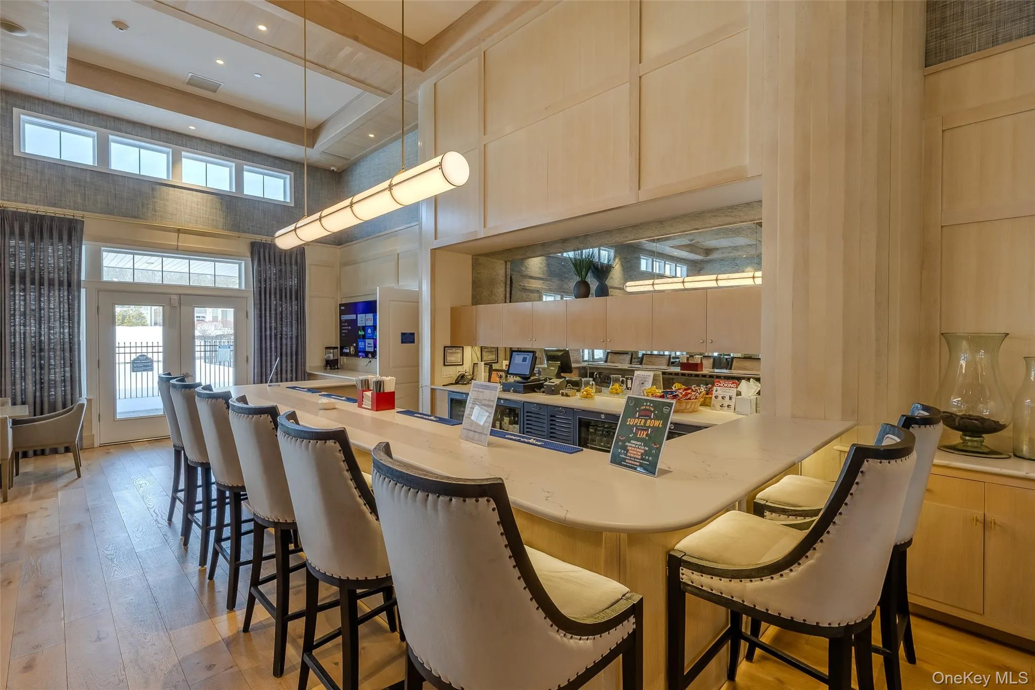 Kitchen with light brown cabinets, french doors, light countertops, a kitchen bar, and a towering ceiling Kitchen with light brown cabinets, french doors, light countertops, a kitchen bar, and a towering ceiling