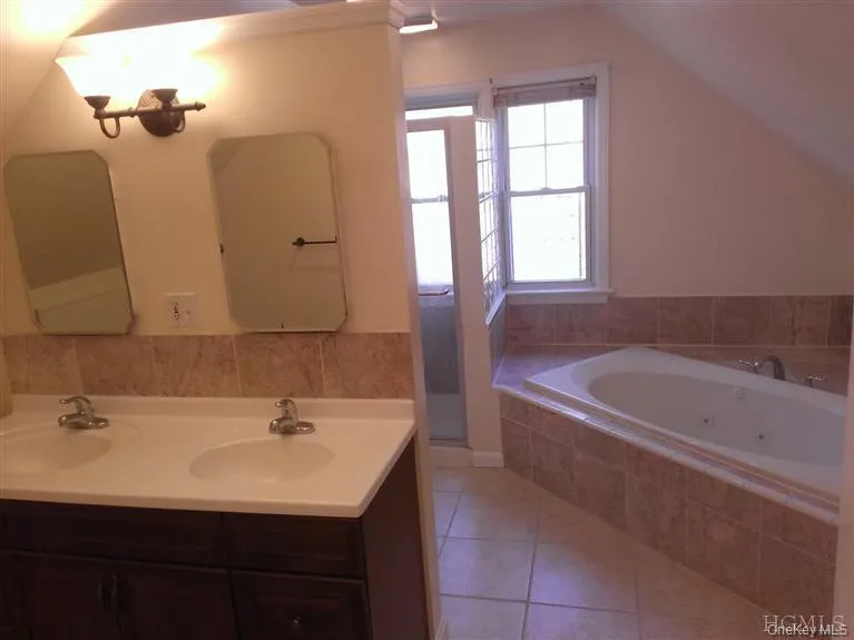 Dual sinks in the front of the master bathroom; behind the 3/4-wall can be seen the frameless glass shower and the spa tub with marble-surround. Lighting has been upgraded with energy-efficient recessed LED retrofit kits. The private master suite, consisting of the master bedroom and this master bath occupy the entire second floor. Dual sinks in the front of the master bathroom; behind the 3/4-wall can be seen the frameless glass shower and the spa tub with marble-surround. Lighting has been upgraded with energy-efficient recessed LED retrofit kits. The private master suite, consisting of the master bedroom and this master bath occupy the entire second floor.