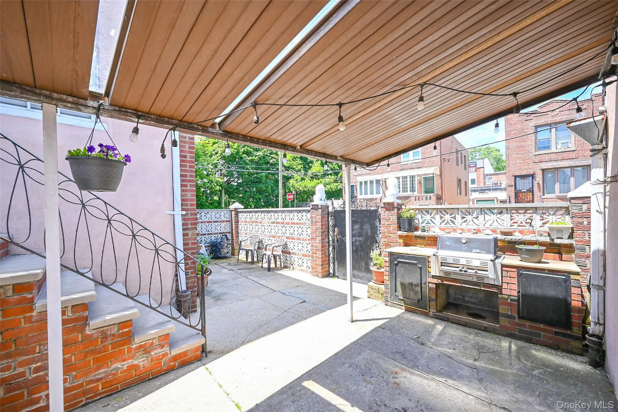 Covered patio area featuring a built-in brick barbecue station with storage, concrete flooring, and decorative perimeter fencing. Covered patio area featuring a built-in brick barbecue station with storage, concrete flooring, and decorative perimeter fencing.