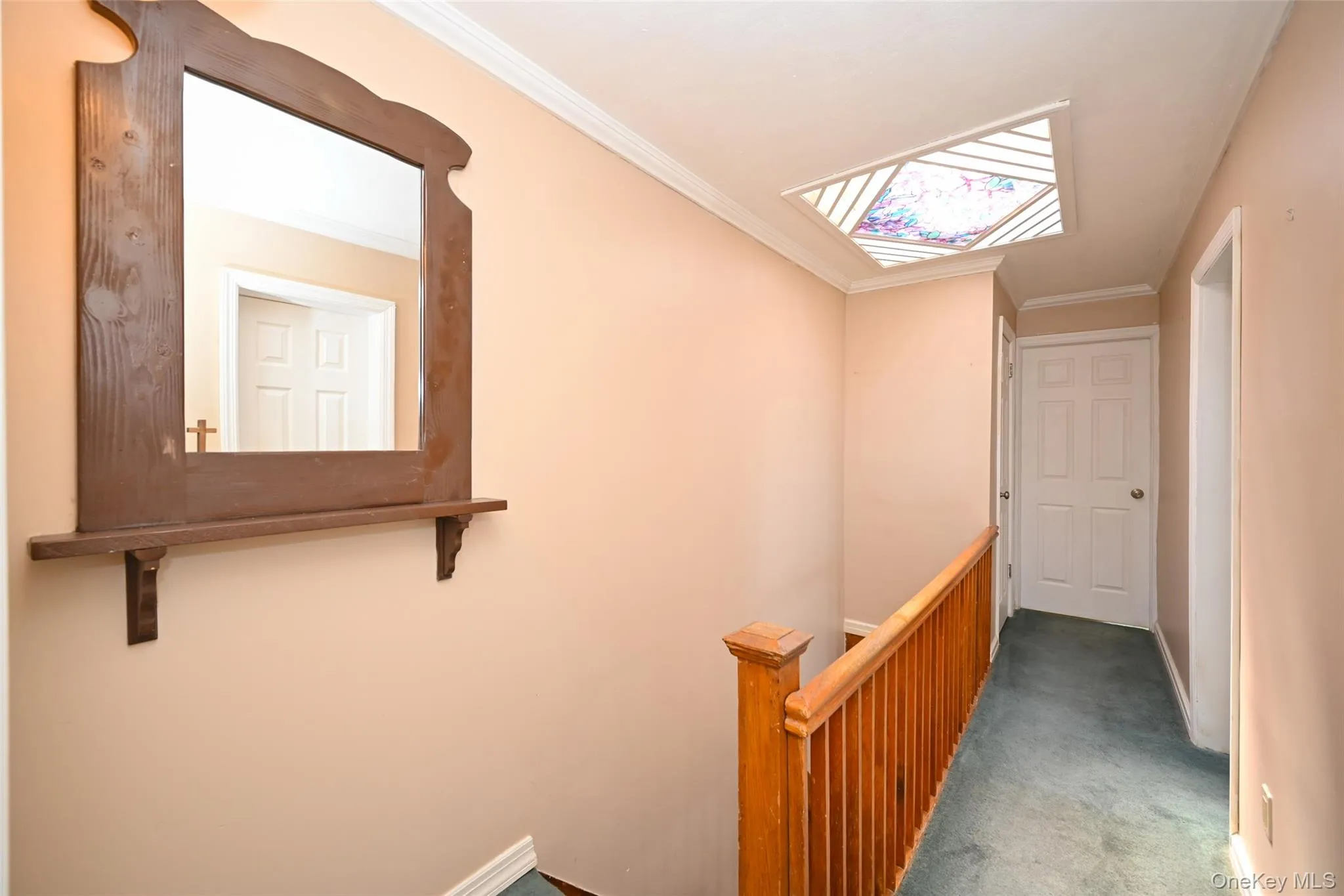 Hallway featuring wood-finish railing, stained glass ceiling detail, and neutral wall tones. Hallway featuring wood-finish railing, stained glass ceiling detail, and neutral wall tones.