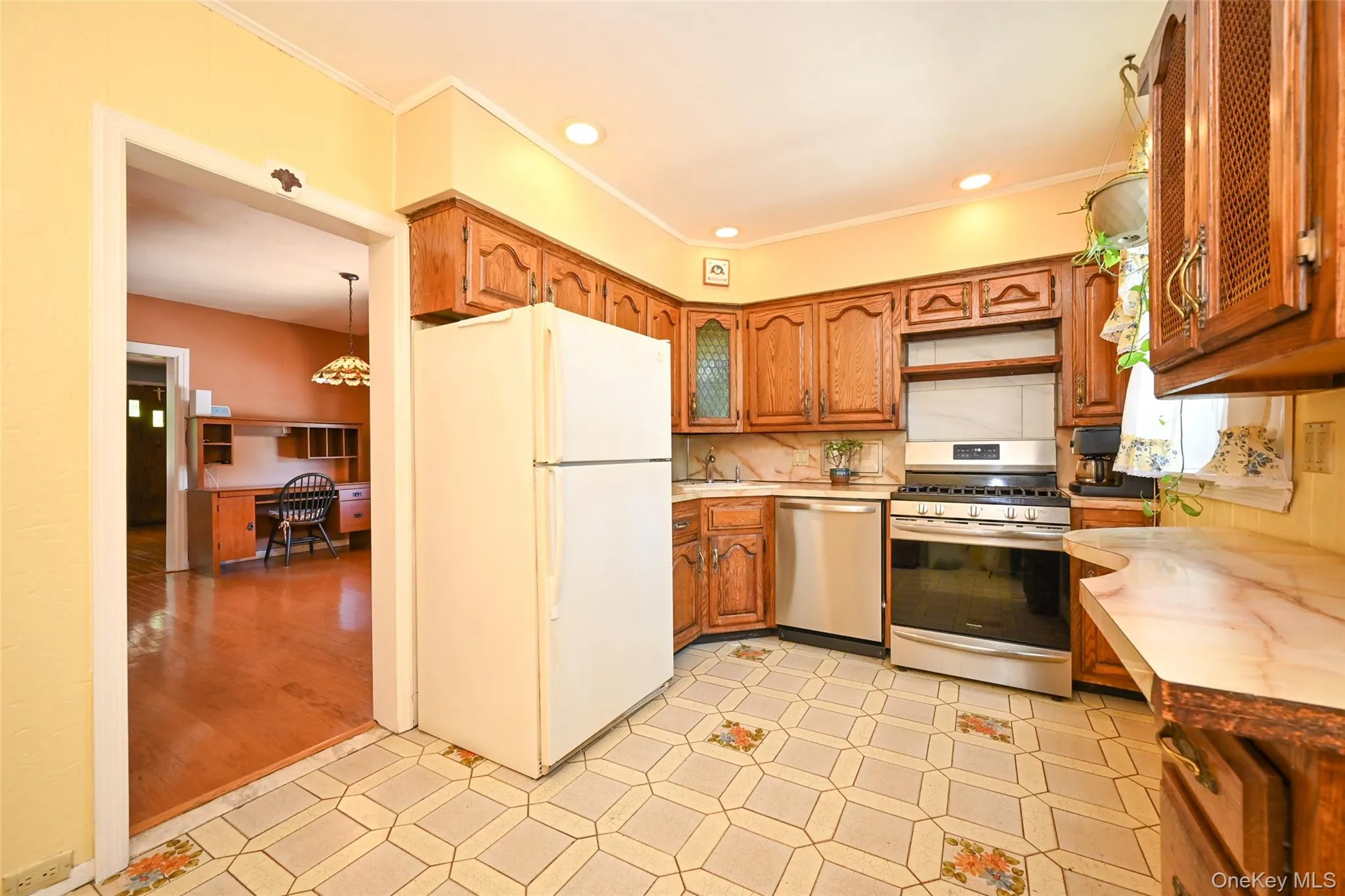 Kitchen featuring wood cabinetry, stainless steel range and dishwasher, patterned floor tiling. Kitchen featuring wood cabinetry, stainless steel range and dishwasher, patterned floor tiling.