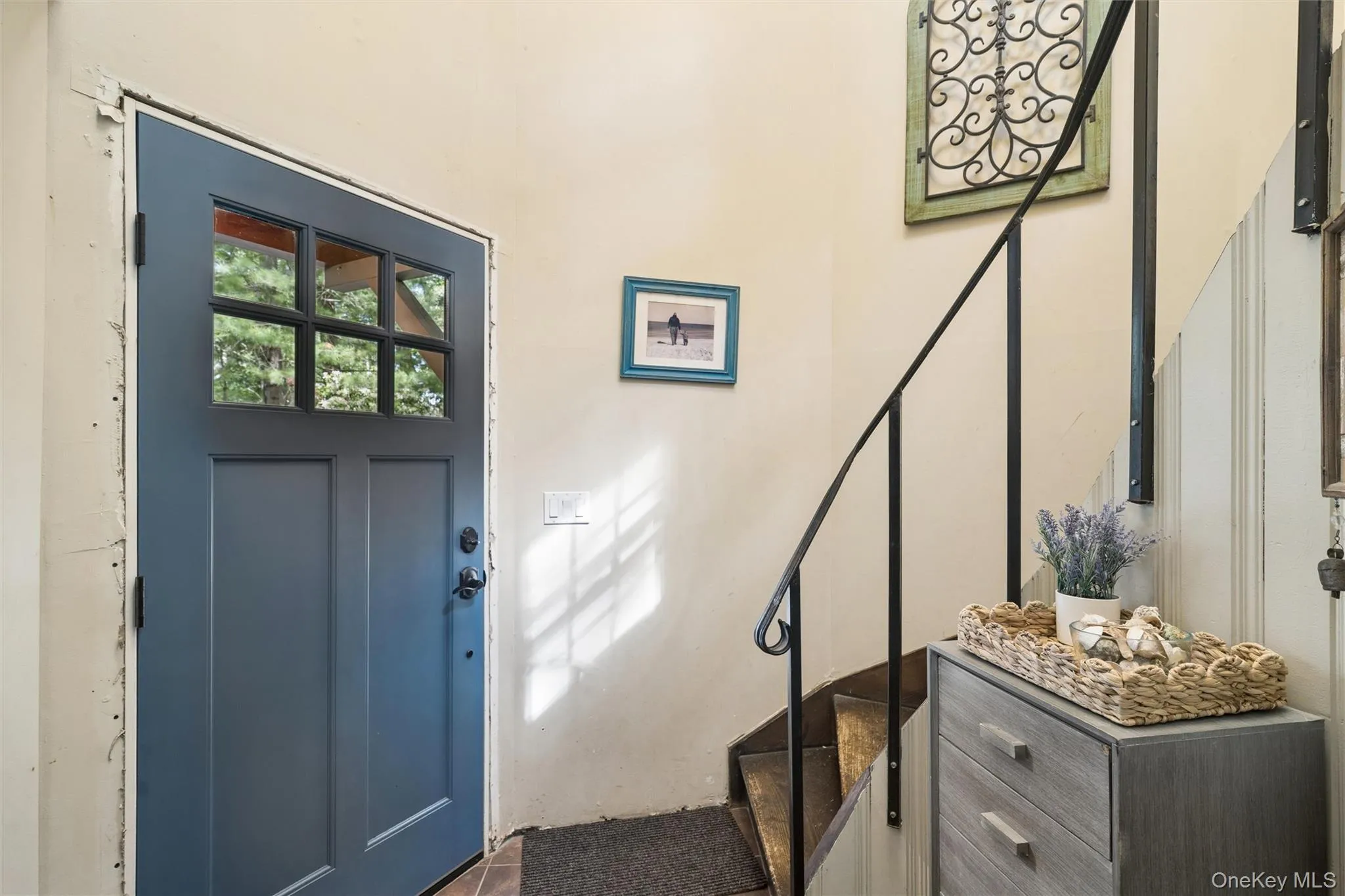 Entryway featuring a paneled door with glass inserts, black hardware, tiled flooring, and a dark metal staircase railing Entryway featuring a paneled door with glass inserts, black hardware, tiled flooring, and a dark metal staircase railing