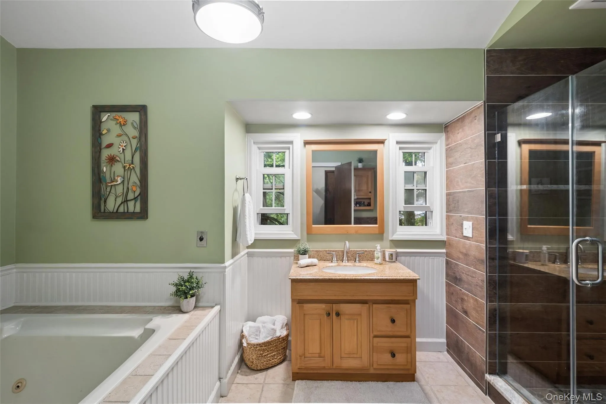 Bathroom featuring a soaking tub, wood vanity with a light-toned countertop, and a glass-enclosed shower with horizontally-stacked tile Bathroom featuring a soaking tub, wood vanity with a light-toned countertop, and a glass-enclosed shower with horizontally-stacked tile