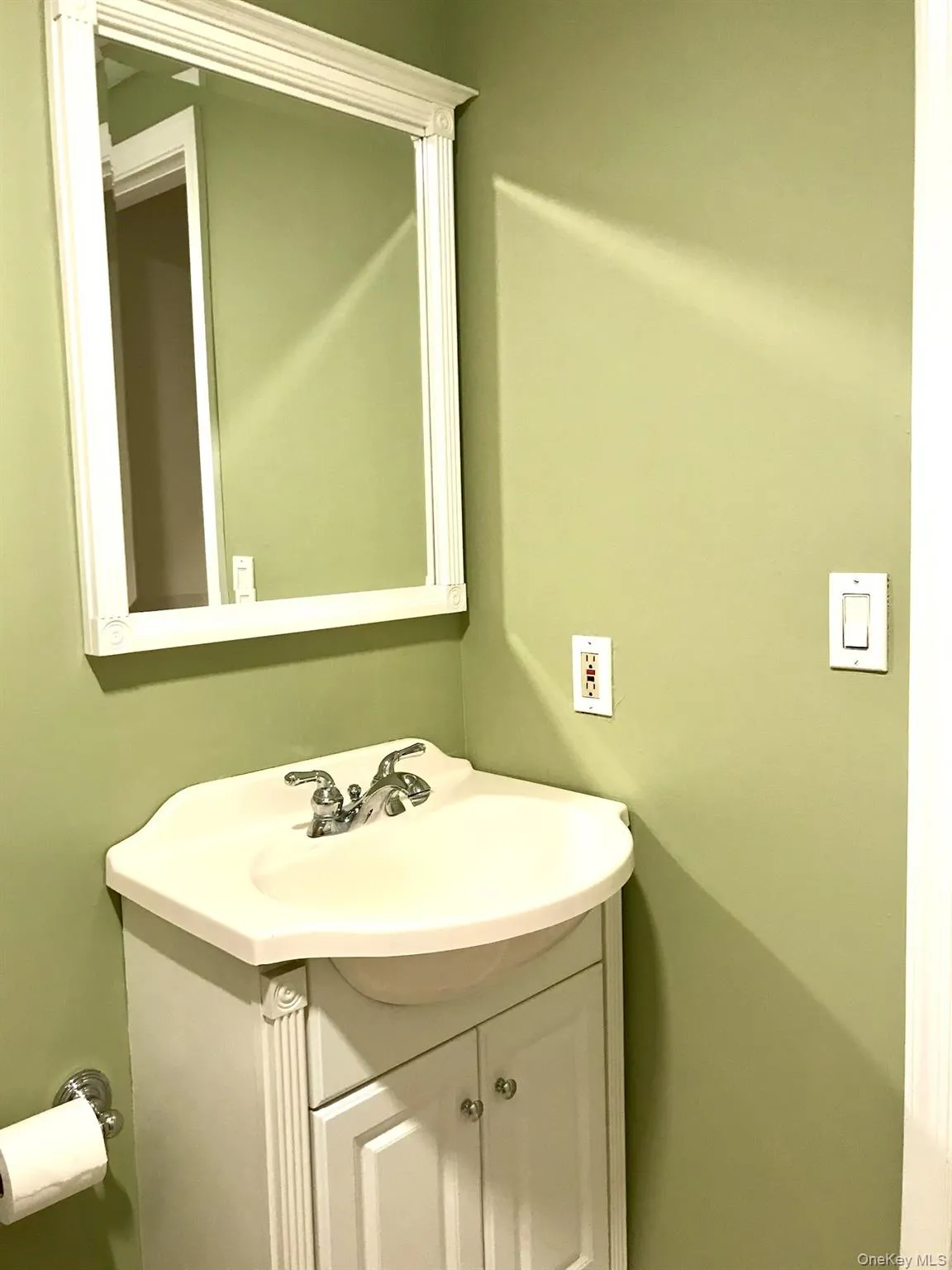 Bathroom vanity featuring a white basin sink with chrome fixtures, set atop a white cabinet with fluted detailing and cabinet doors with silver-tone hardware Bathroom vanity featuring a white basin sink with chrome fixtures, set atop a white cabinet with fluted detailing and cabinet doors with silver-tone hardware