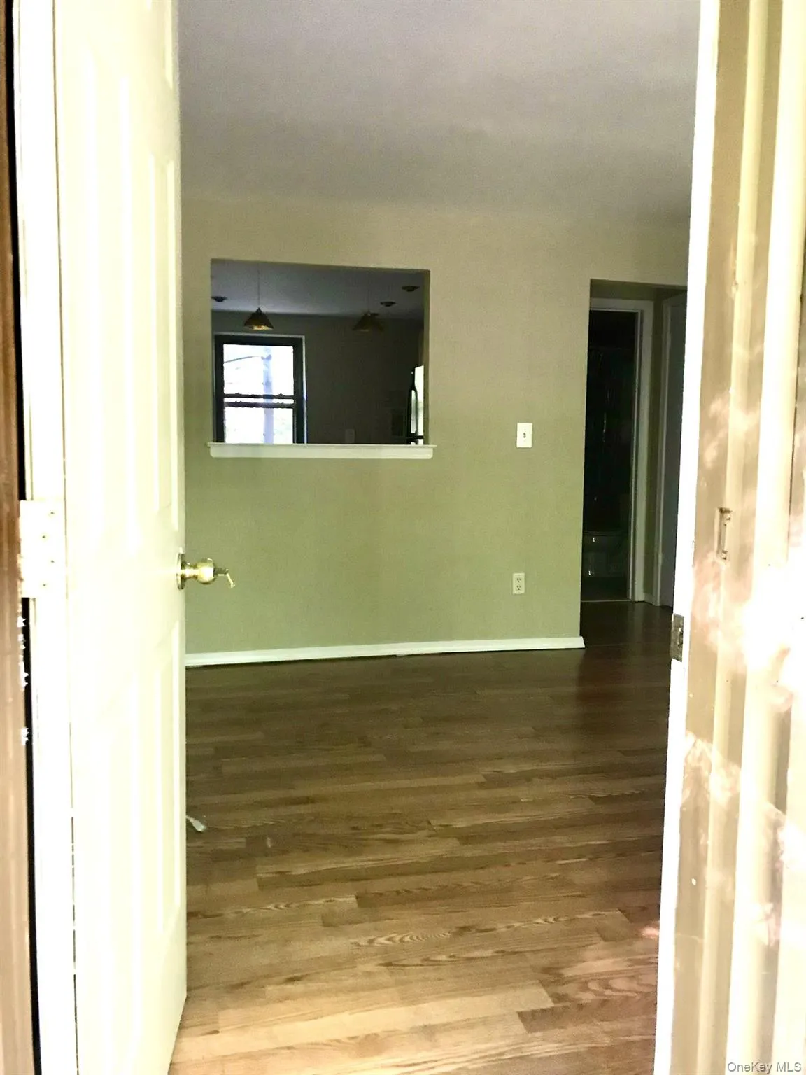 Hardwood flooring throughout, with a pass-through window featuring a white ledge Hardwood flooring throughout, with a pass-through window featuring a white ledge
