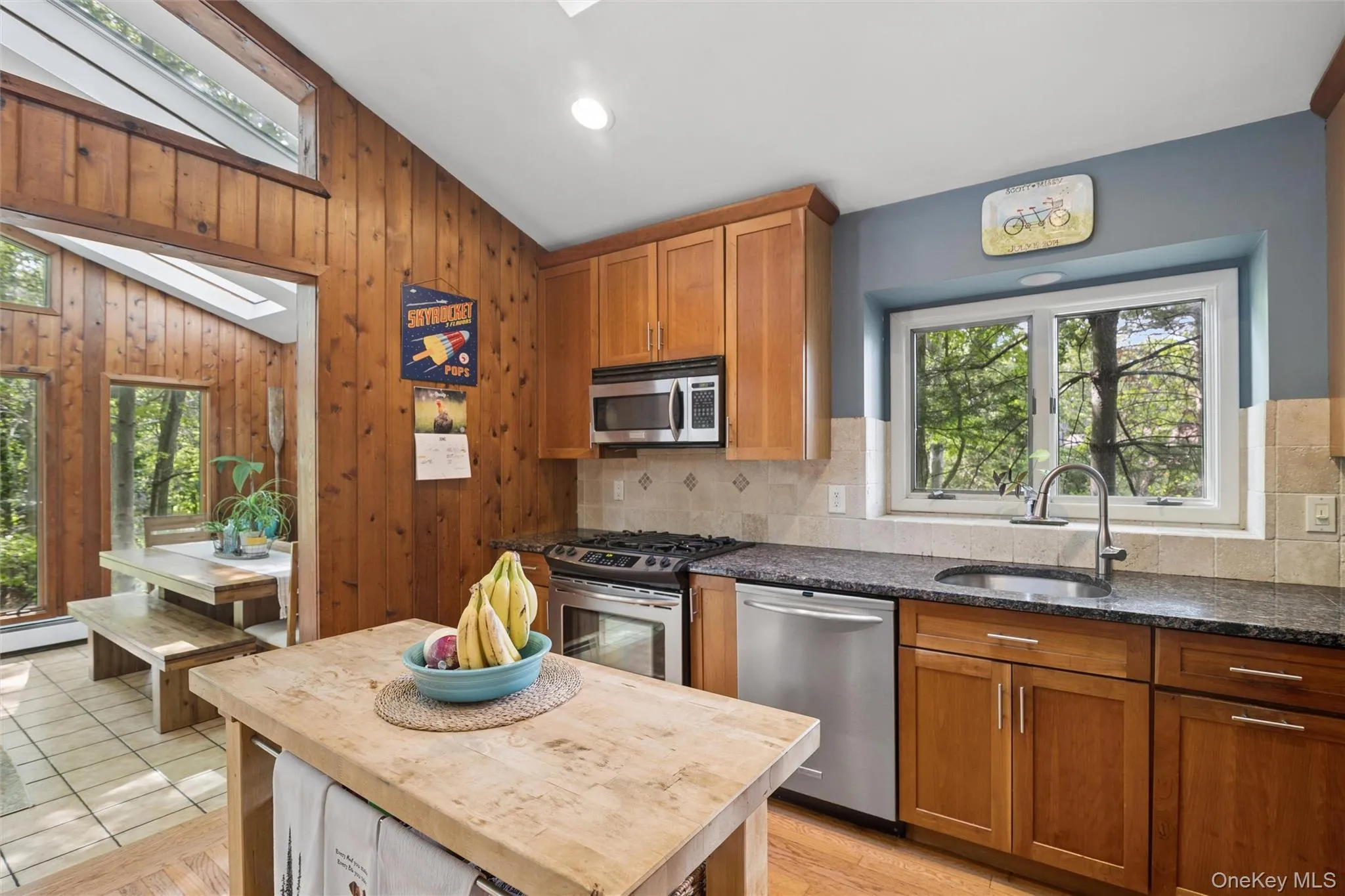 Kitchen featuring wood-paneled walls, a butcher block island, and granite countertops Kitchen featuring wood-paneled walls, a butcher block island, and granite countertops