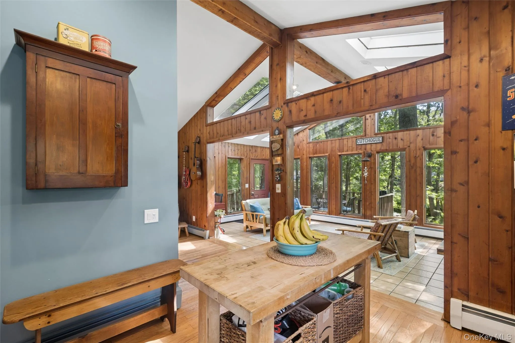 Vaulted ceilings featuring exposed wood beams and skylights, a large picture window, and wood-finish flooring Vaulted ceilings featuring exposed wood beams and skylights, a large picture window, and wood-finish flooring