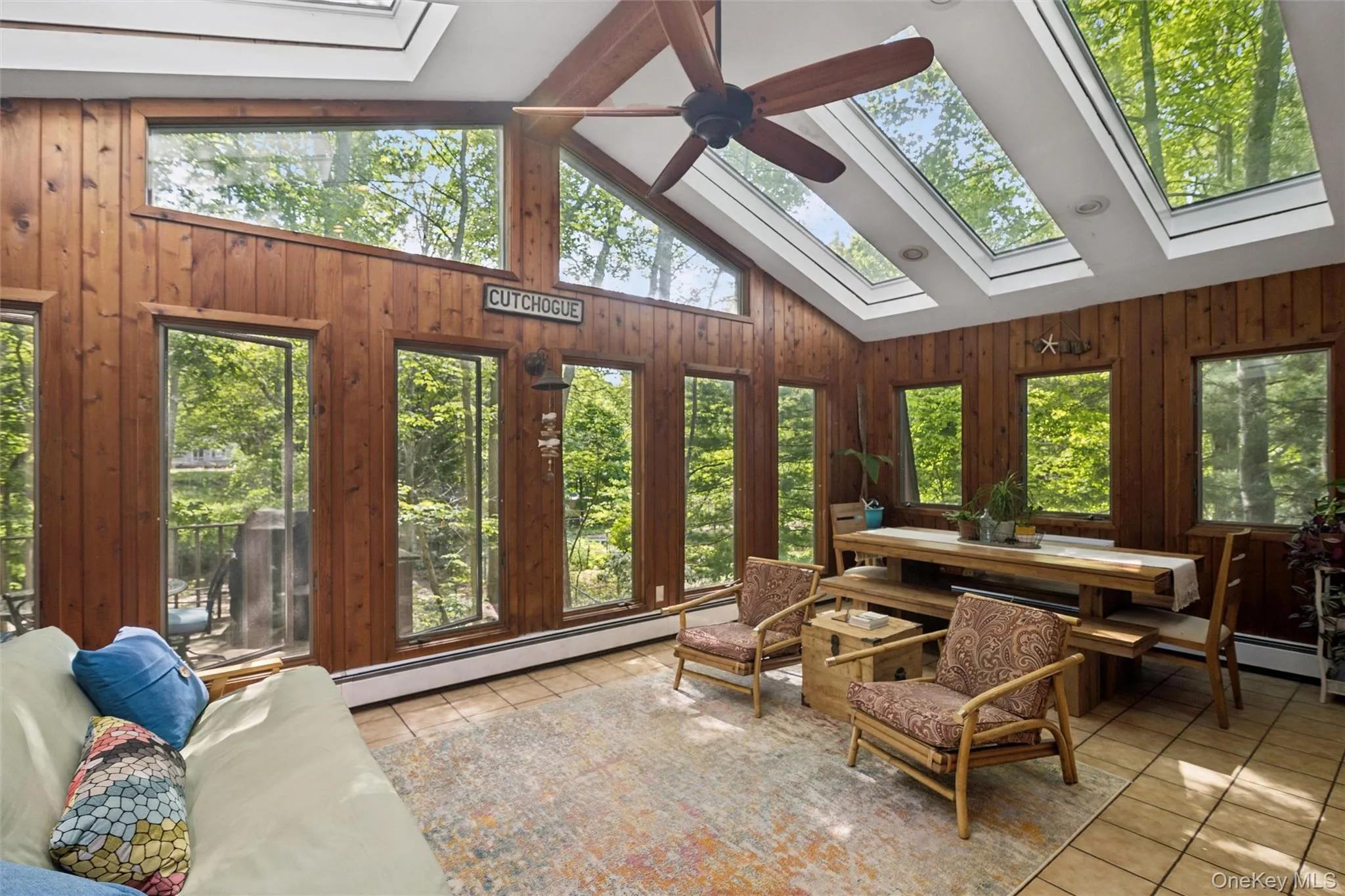 Sunroom with wood paneling, multiple skylights, and a vaulted ceiling with a large ceiling fan Sunroom with wood paneling, multiple skylights, and a vaulted ceiling with a large ceiling fan