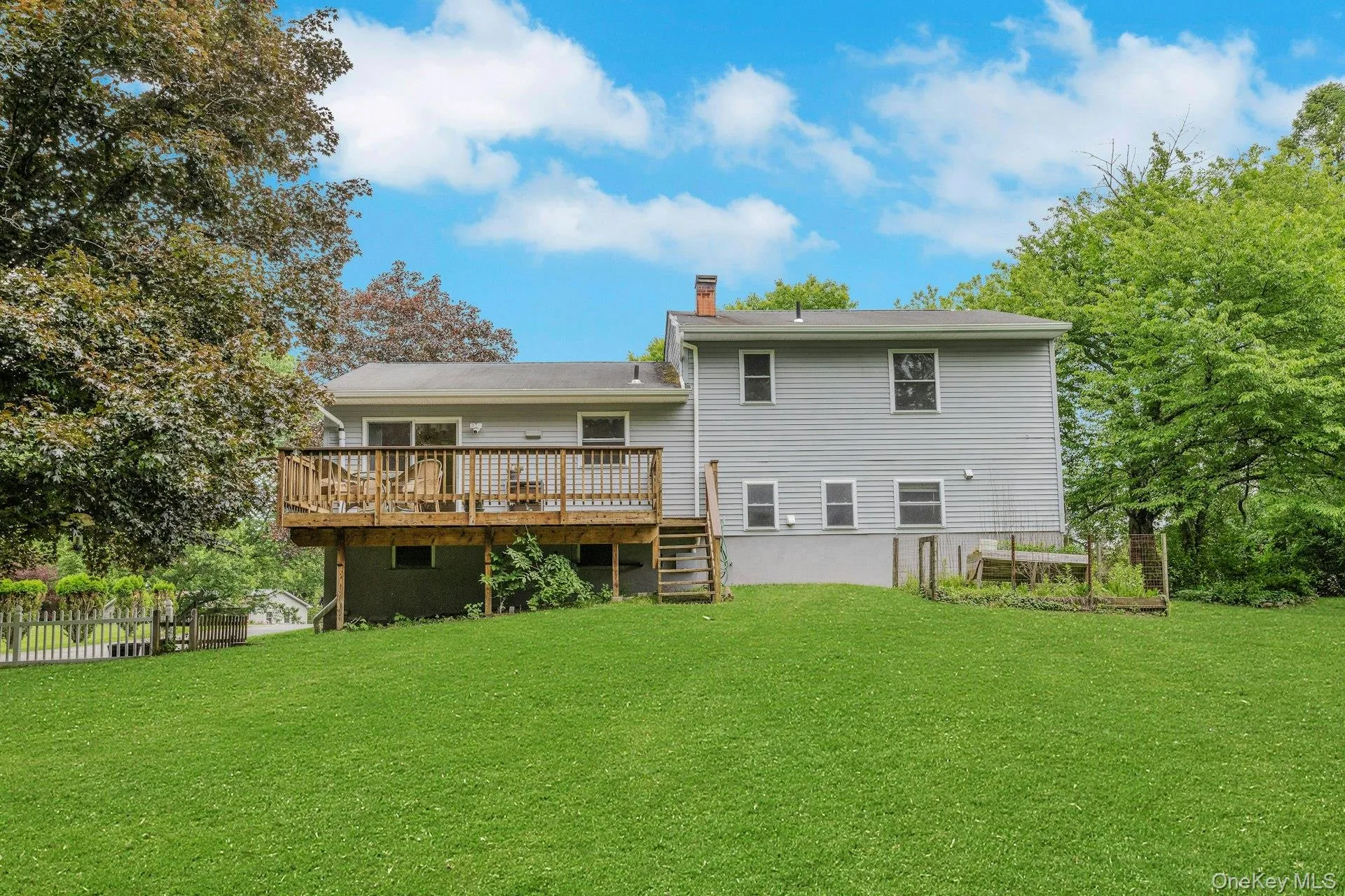 Expansive green lawn with a wood deck and stairs. Expansive green lawn with a wood deck and stairs.