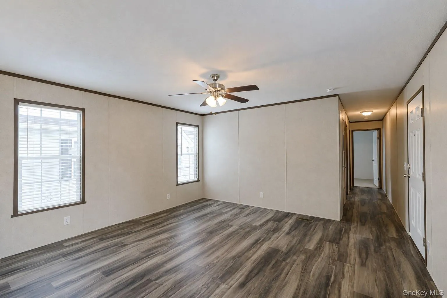 Spacious interior featuring wood-finish flooring, light-toned walls, and dark trim Spacious interior featuring wood-finish flooring, light-toned walls, and dark trim