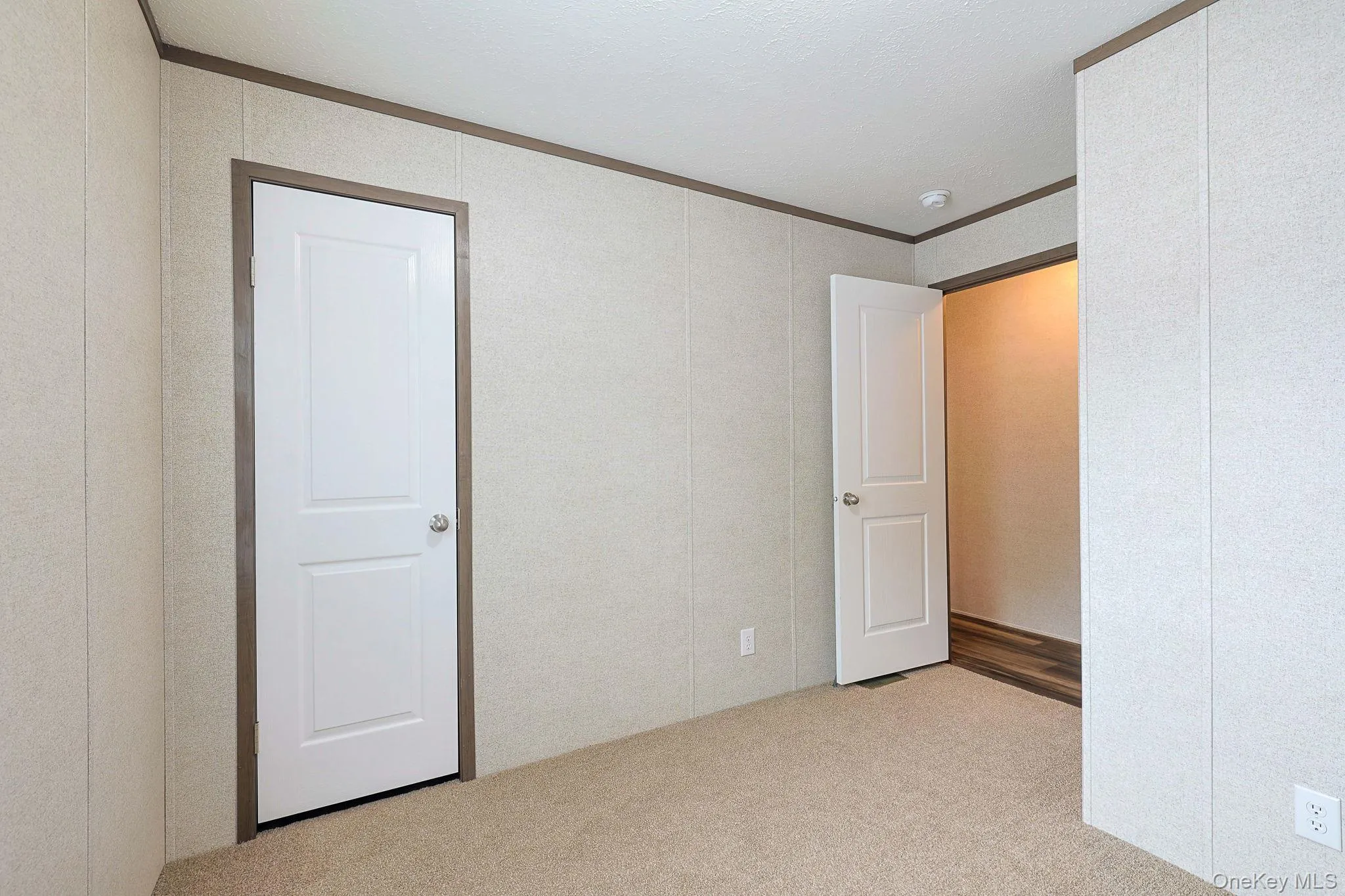 Spacious interior featuring wood-finish flooring, light-toned walls, and dark trim Spacious interior featuring wood-finish flooring, light-toned walls, and dark trim