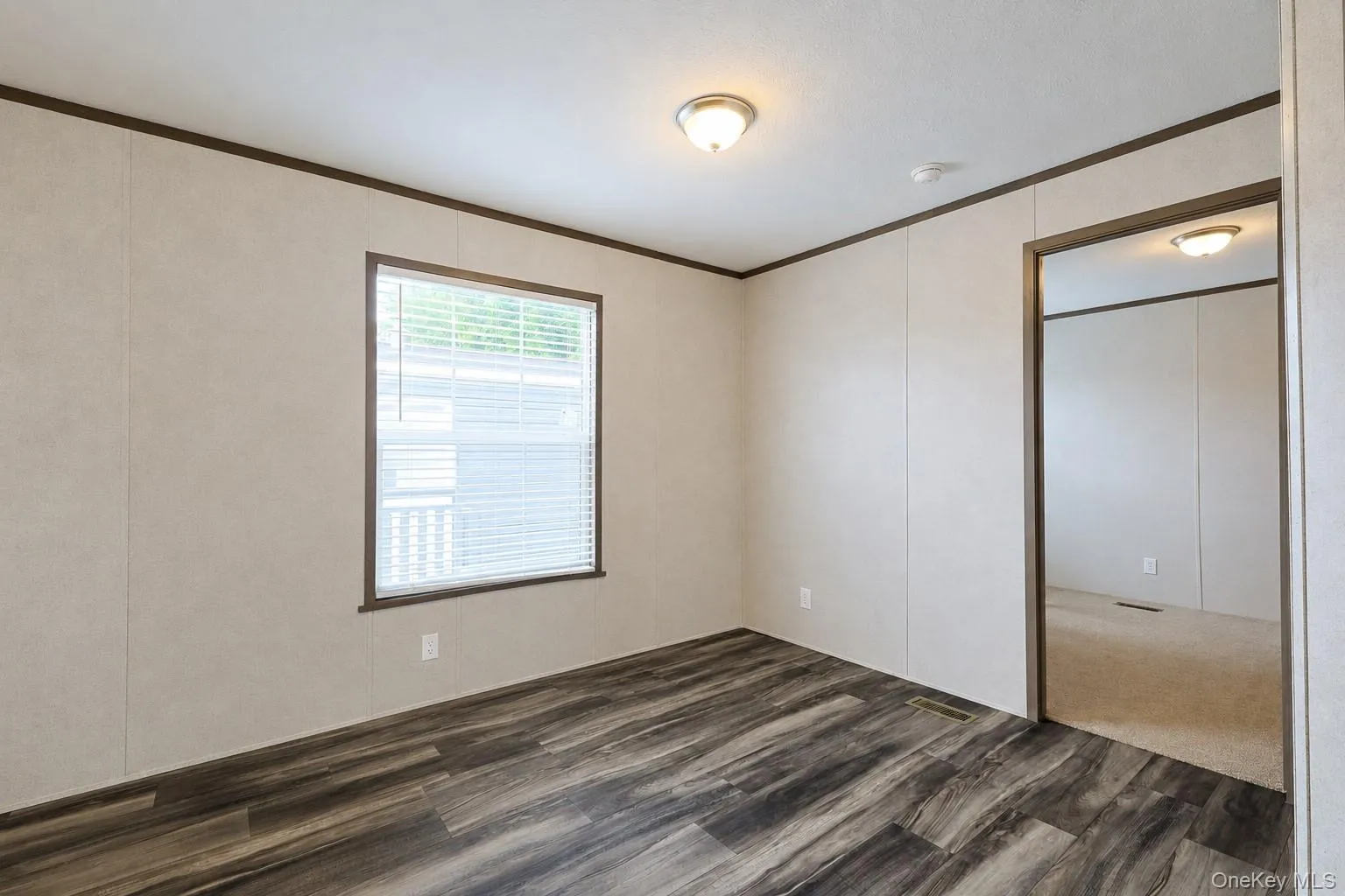 Spacious interior featuring wood-finish flooring, light-toned walls, and dark trim Spacious interior featuring wood-finish flooring, light-toned walls, and dark trim