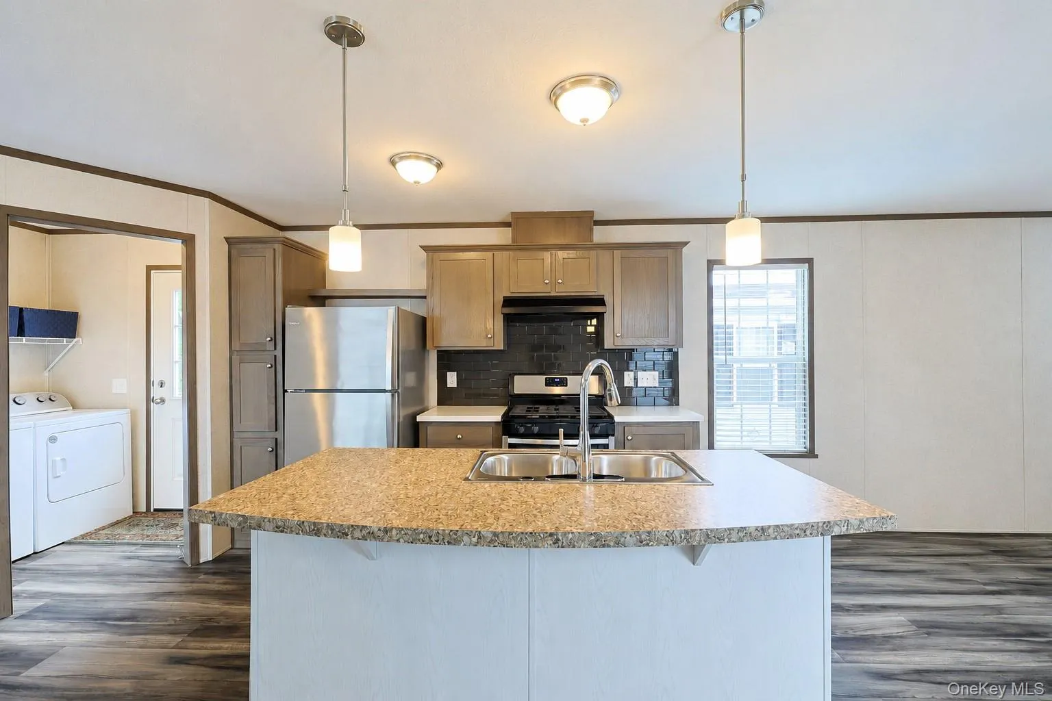 Kitchen featuring an island with a double basin sink, stainless steel faucet, and granite-finish countertop Kitchen featuring an island with a double basin sink, stainless steel faucet, and granite-finish countertop