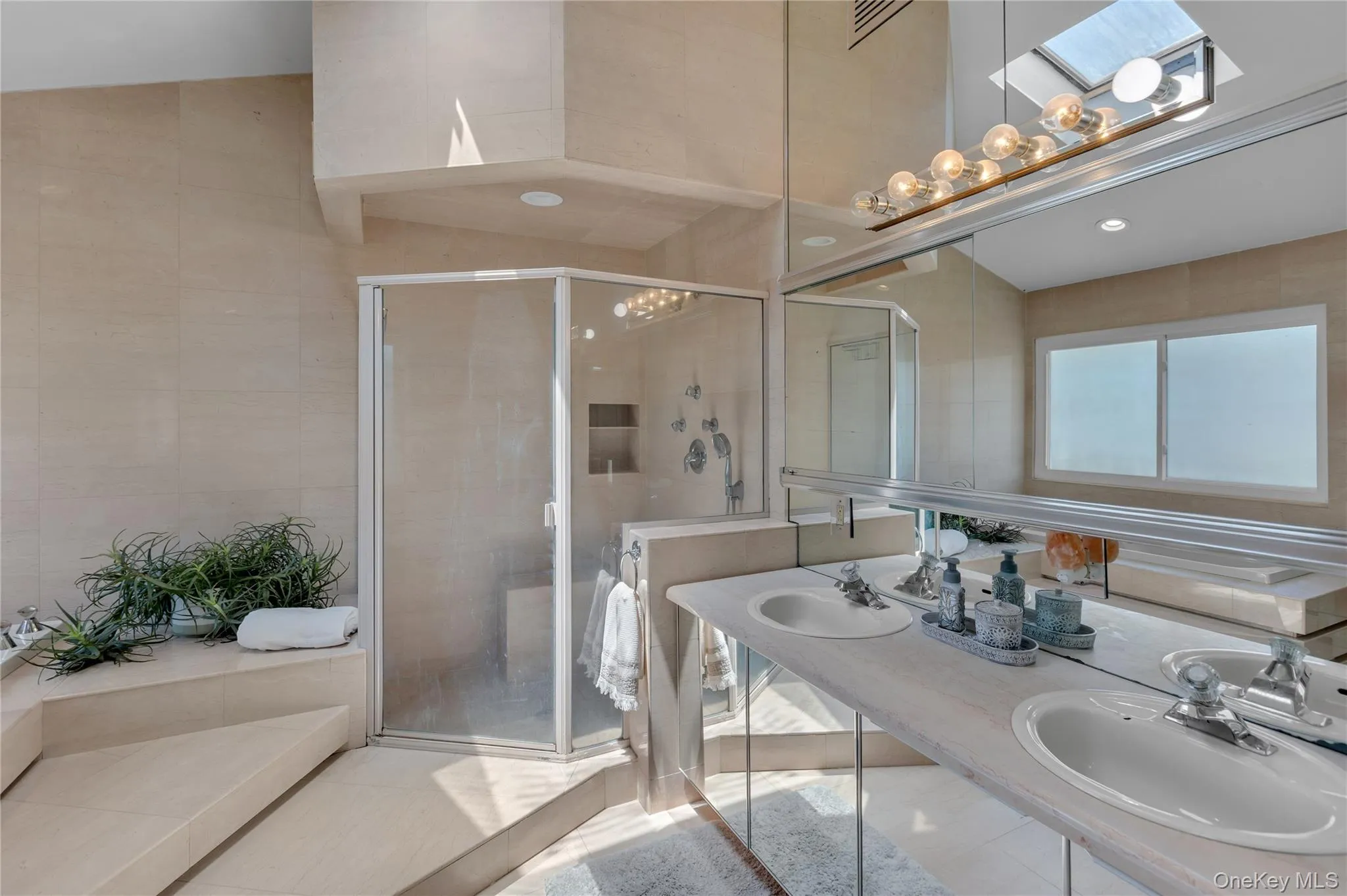 Dual vanity with integrated sinks and chrome fixtures, framed by a wall-mounted mirror Dual vanity with integrated sinks and chrome fixtures, framed by a wall-mounted mirror