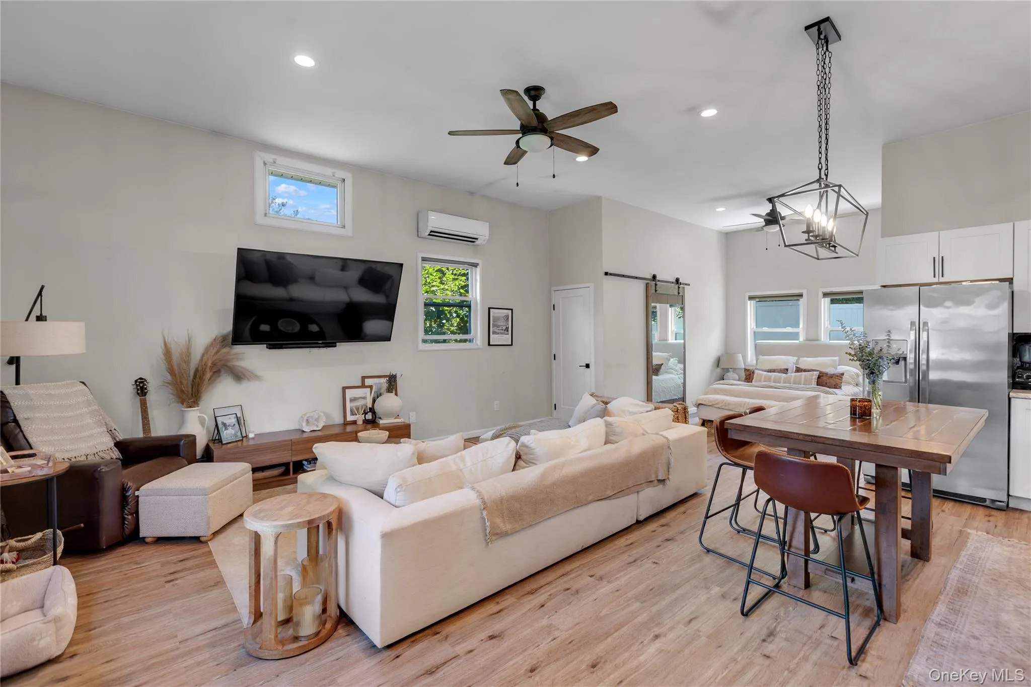 Open-concept living space with wood-finish flooring, high ceilings, and recessed lighting Open-concept living space with wood-finish flooring, high ceilings, and recessed lighting