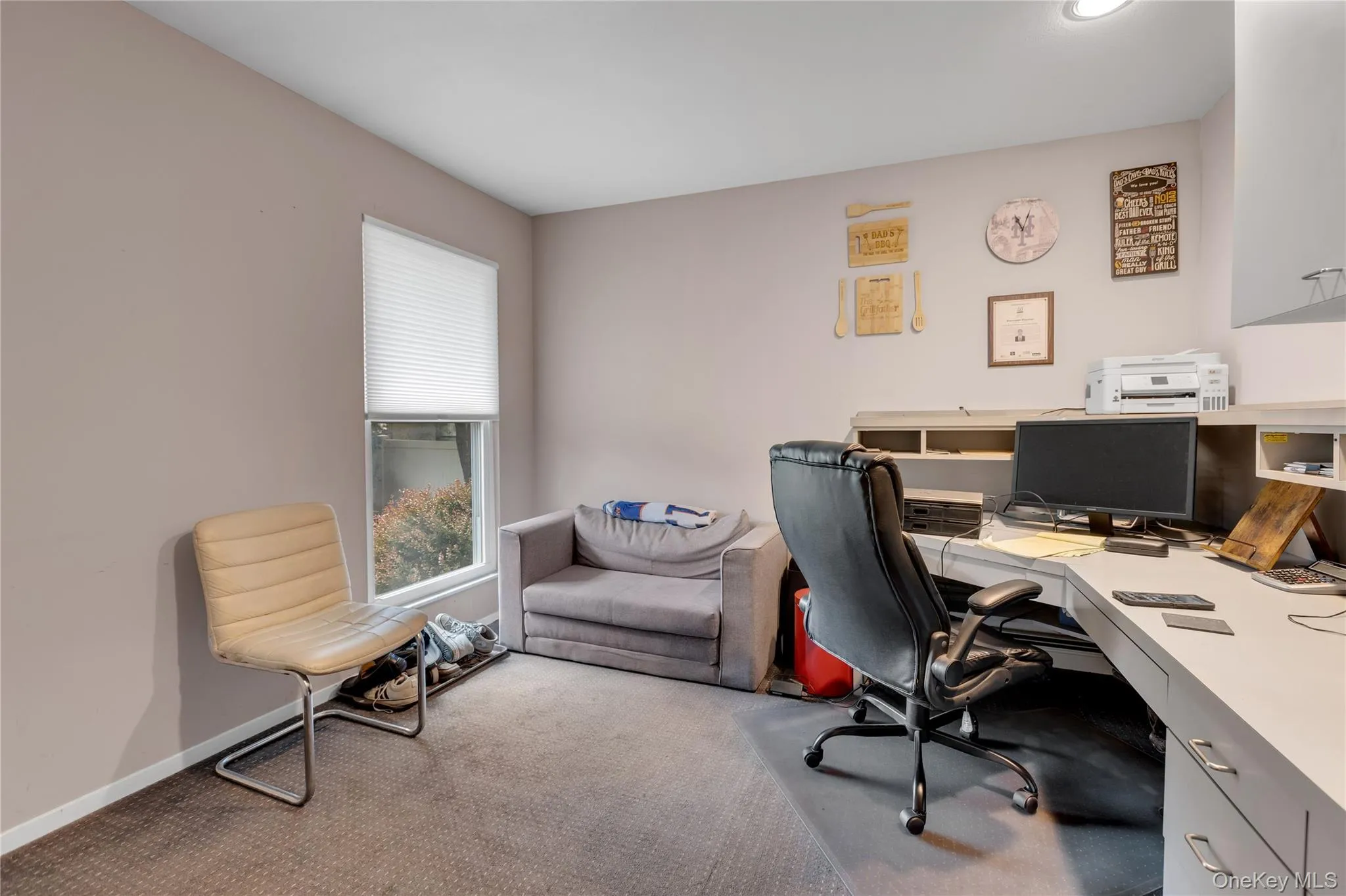 Dedicated workspace featuring a built-in desk with integrated shelving, recessed lighting, and a single window with blinds Dedicated workspace featuring a built-in desk with integrated shelving, recessed lighting, and a single window with blinds