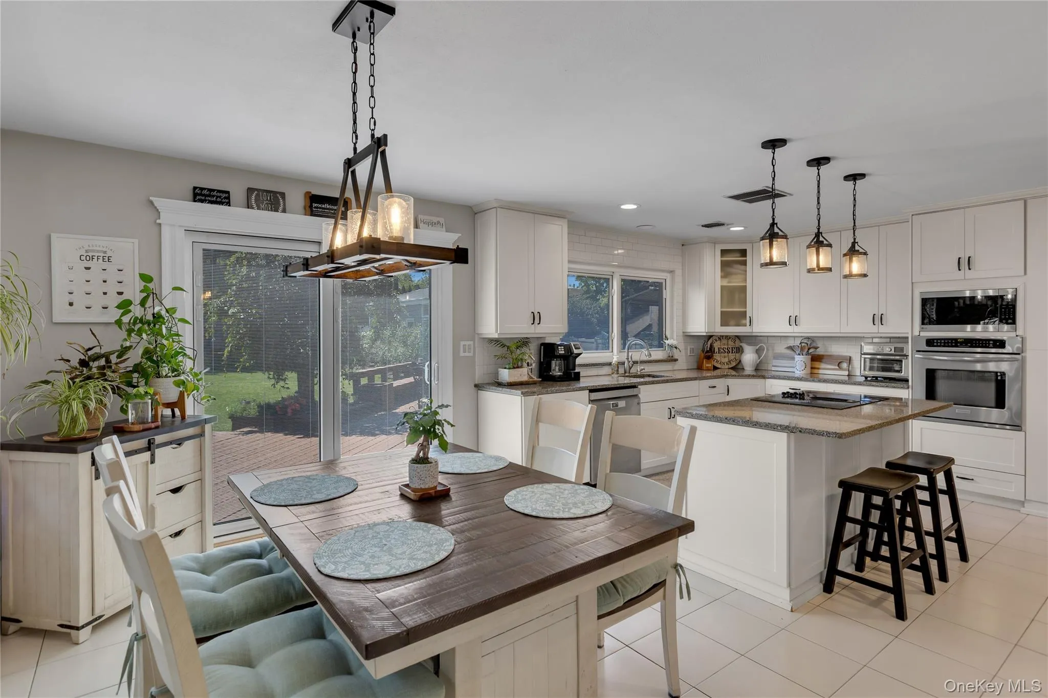 Kitchen and dining area featuring white cabinetry, stainless steel appliances, a center island with countertop seating, and a sliding glass door to exterior Kitchen and dining area featuring white cabinetry, stainless steel appliances, a center island with countertop seating, and a sliding glass door to exterior