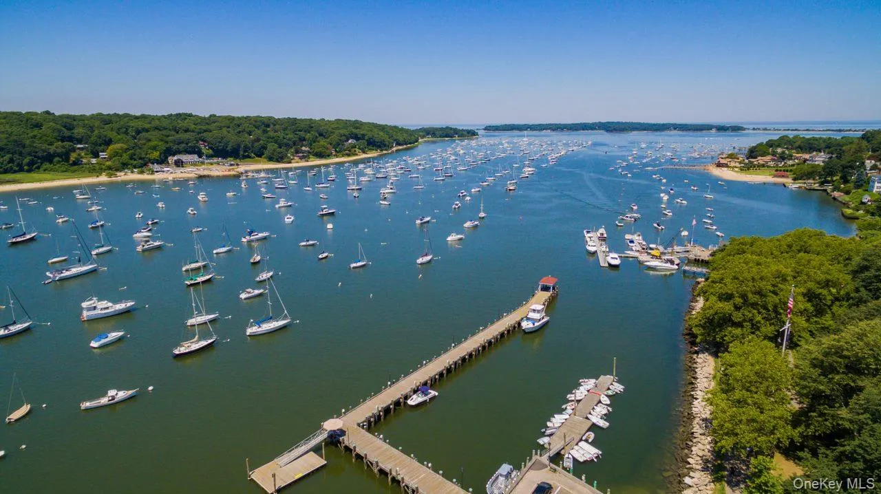 Expansive waterfront setting featuring a long wooden dock with multiple boat slips, numerous anchored boats, and a lush, tree-lined shoreline Expansive waterfront setting featuring a long wooden dock with multiple boat slips, numerous anchored boats, and a lush, tree-lined shoreline