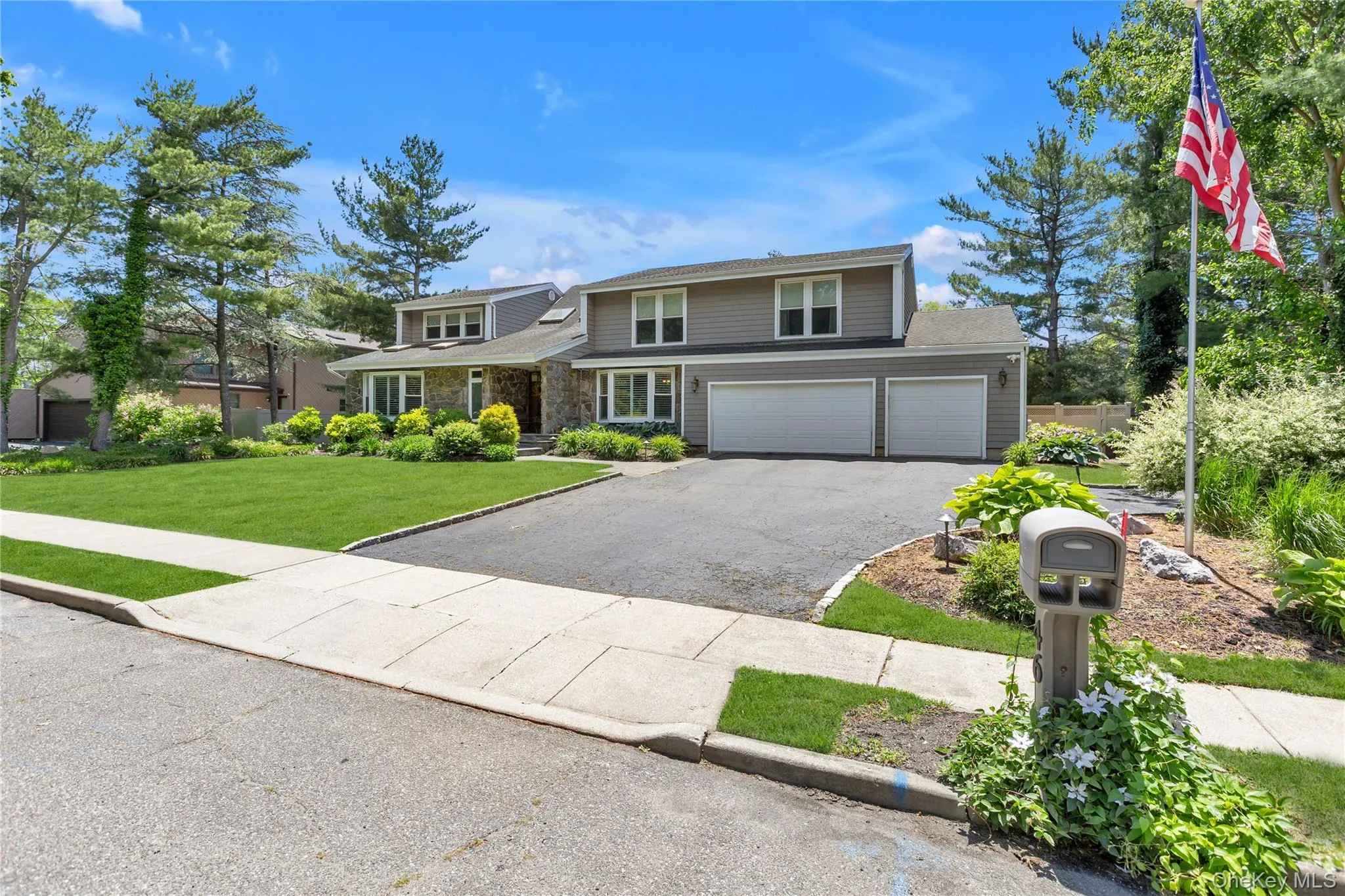 Multi-level residence featuring stone and siding exterior, a two-car garage, and an asphalt driveway Multi-level residence featuring stone and siding exterior, a two-car garage, and an asphalt driveway