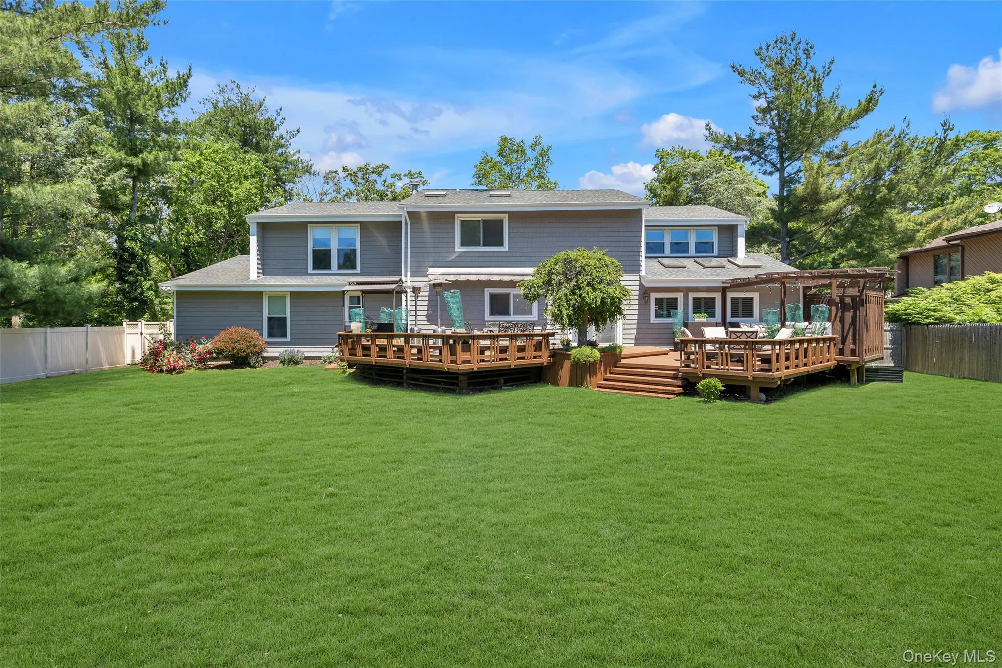 Expansive green lawn with a multi-level wood deck and pergola structure Expansive green lawn with a multi-level wood deck and pergola structure