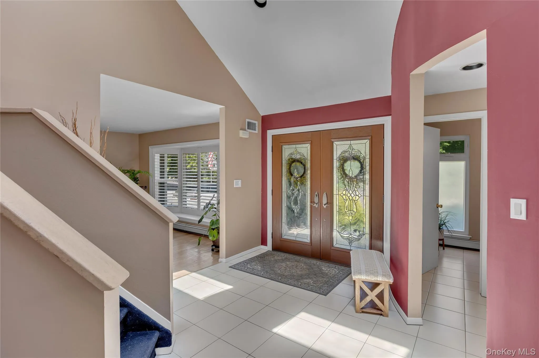 Tiled entryway with double doors featuring decorative glass inserts Tiled entryway with double doors featuring decorative glass inserts
