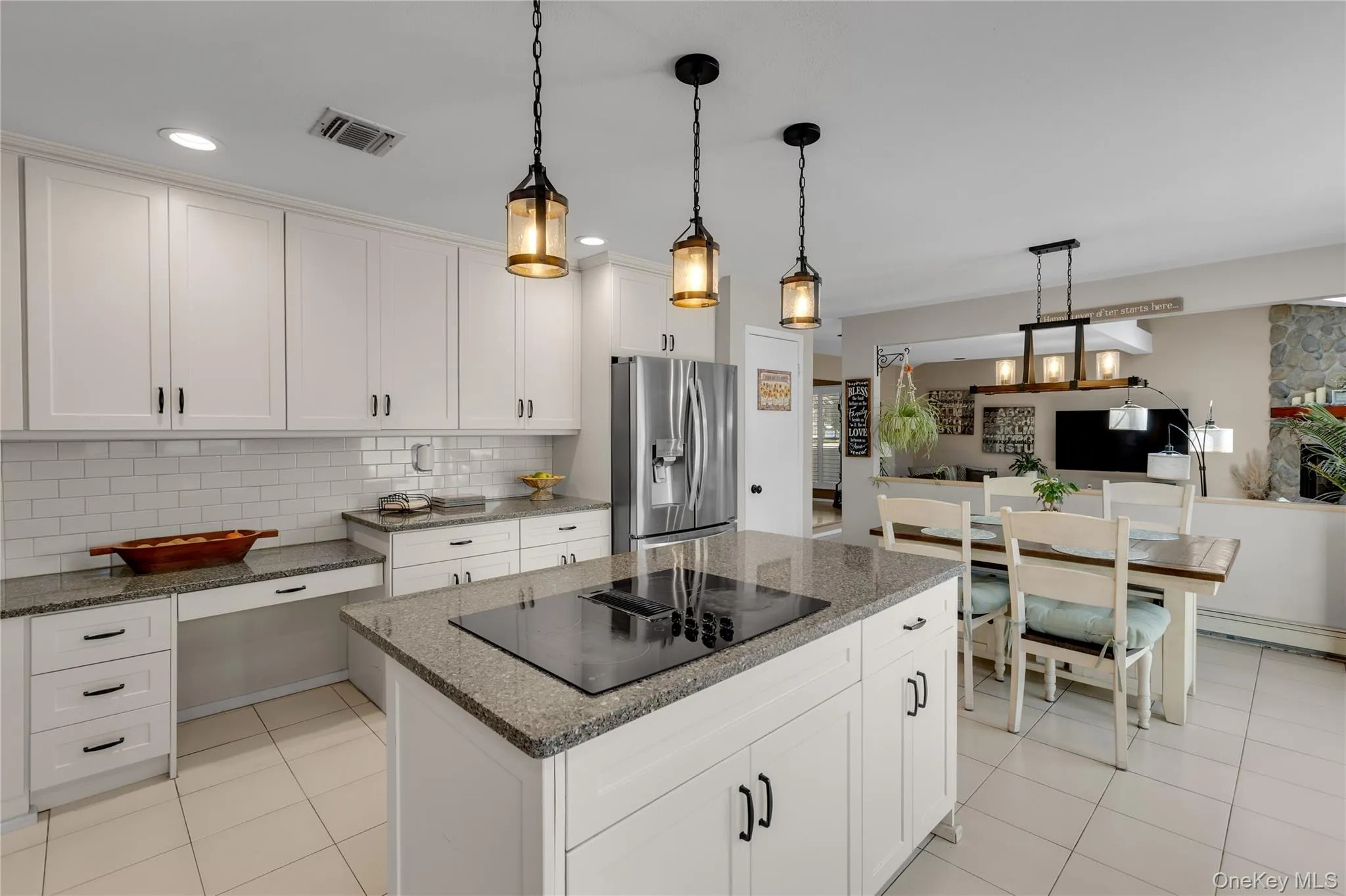 Kitchen featuring white shaker cabinetry, granite countertops, a subway tile backsplash, a center island with an integrated cooktop, and recessed and pendant lighting Kitchen featuring white shaker cabinetry, granite countertops, a subway tile backsplash, a center island with an integrated cooktop, and recessed and pendant lighting